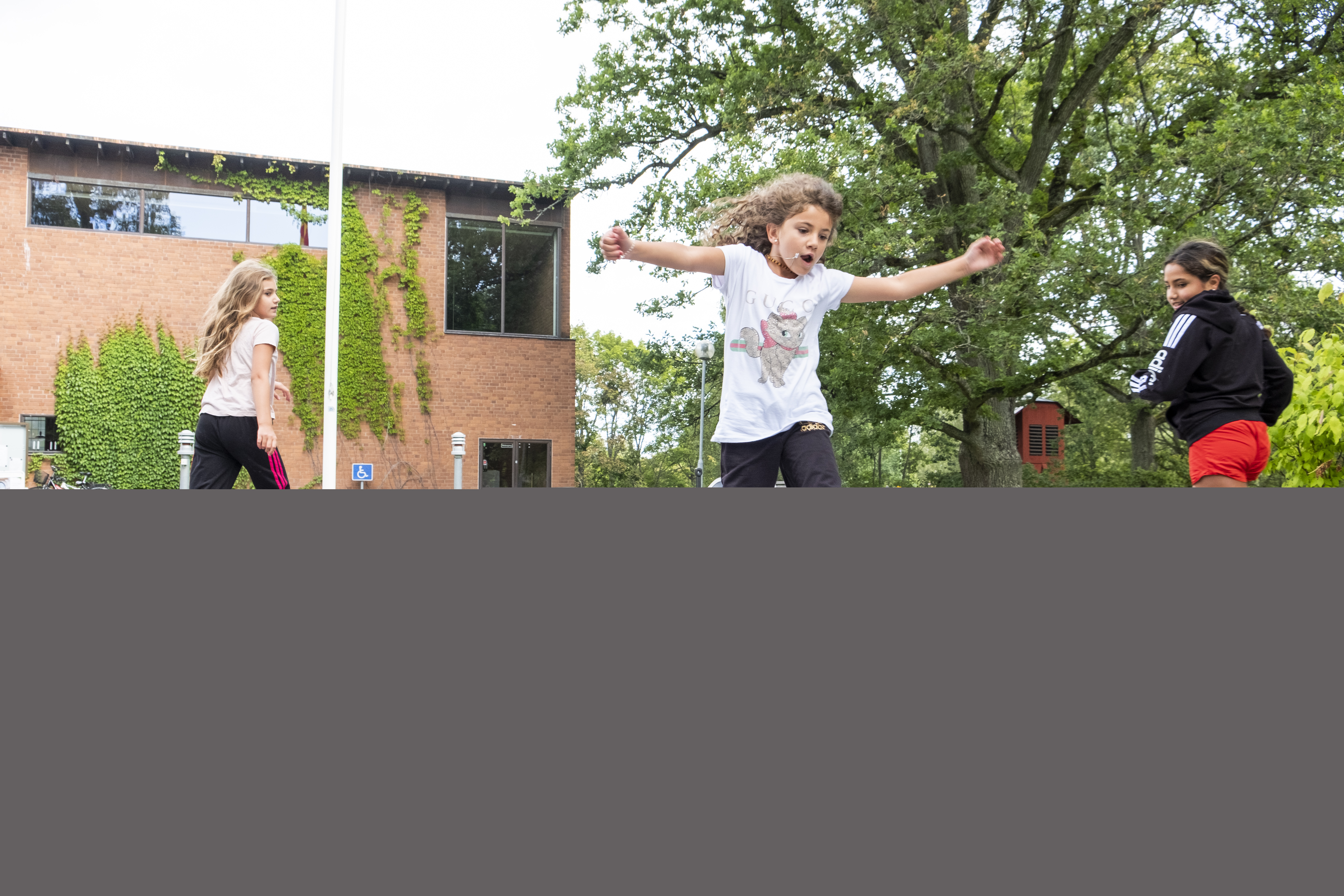 Flicka som hoppar på utritade rutor i asfalten