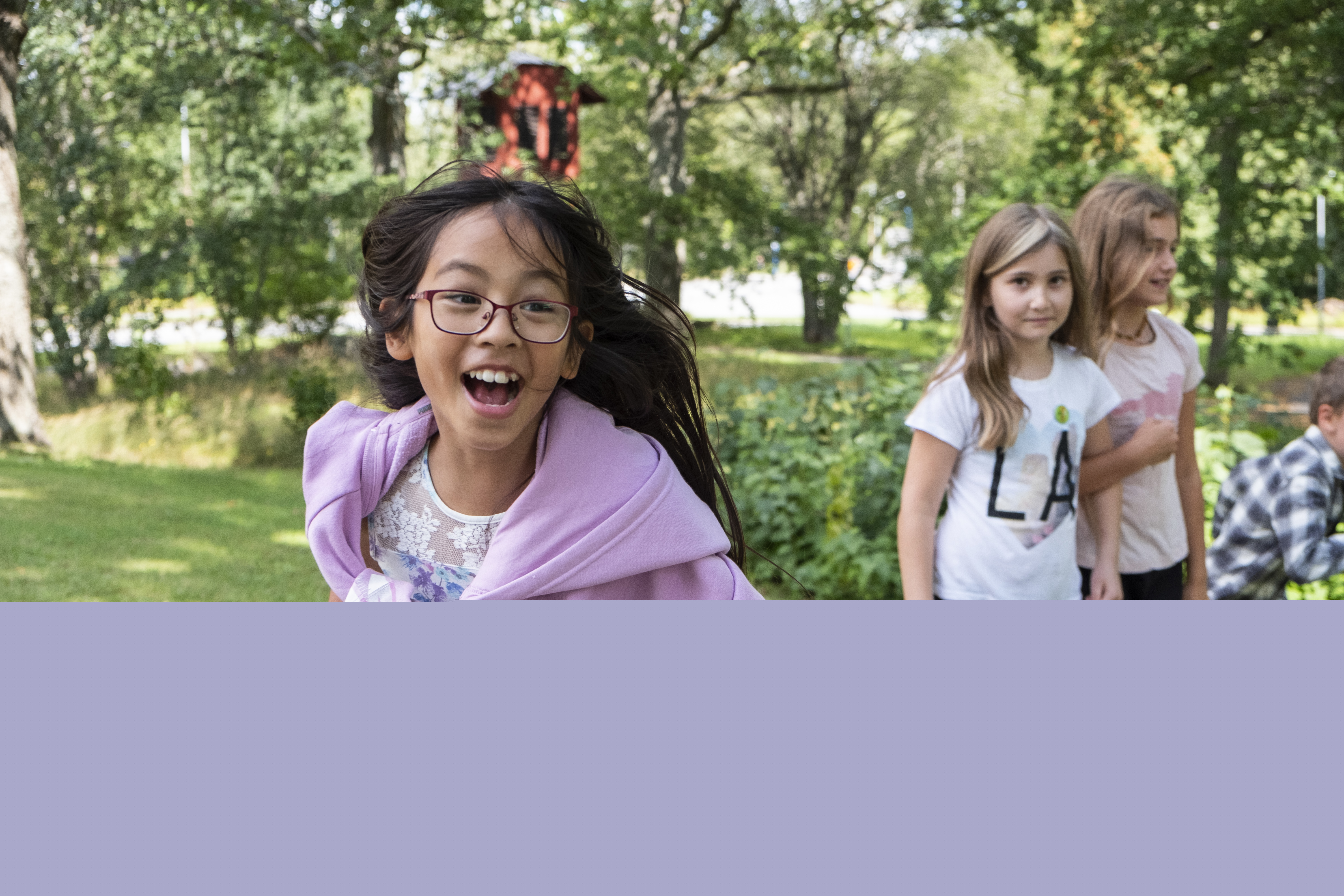 Flicka med glasögon och lila tröja springer mot kameran