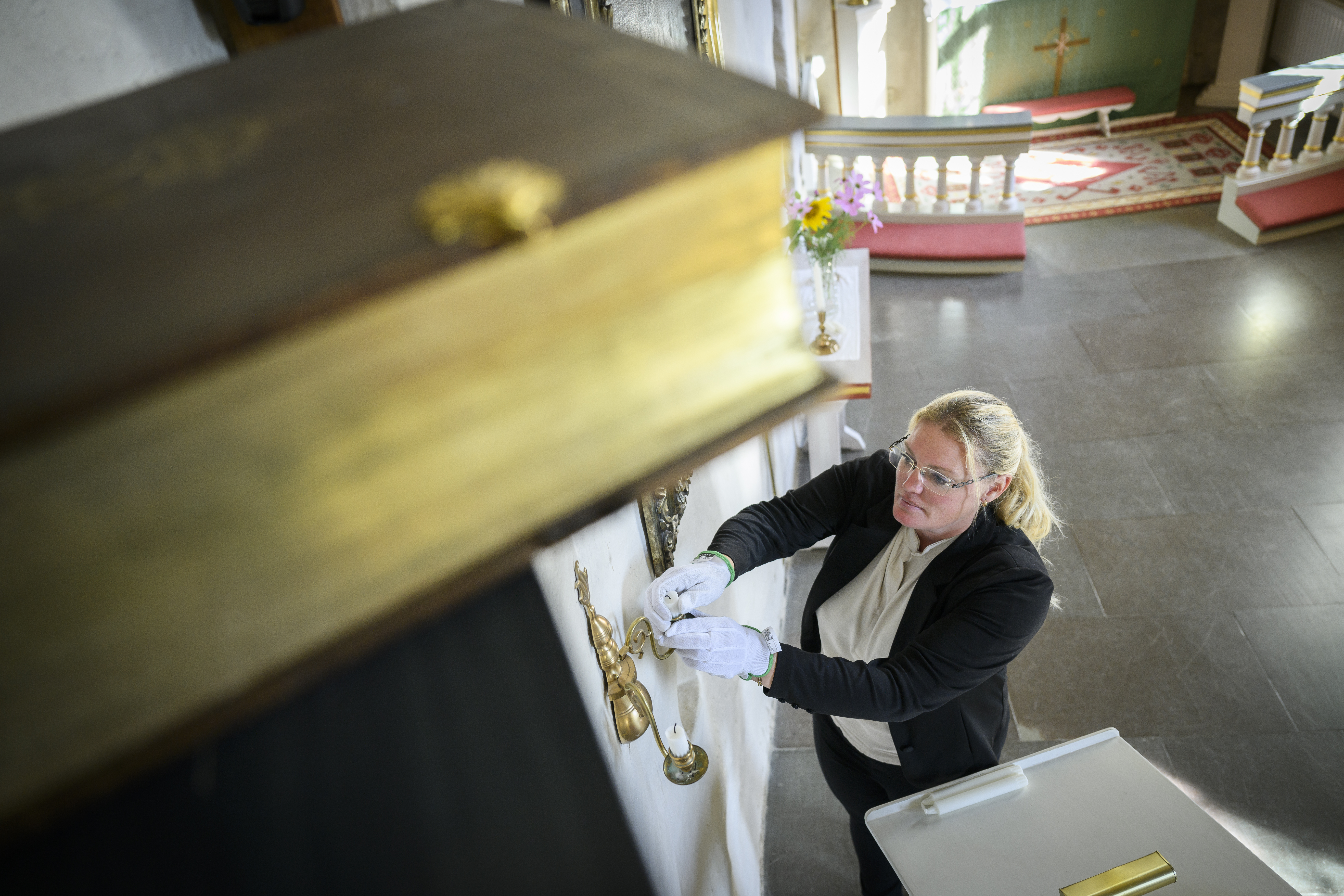 Kyrkovaktmästare som putsar ljusstakar i kyrkan