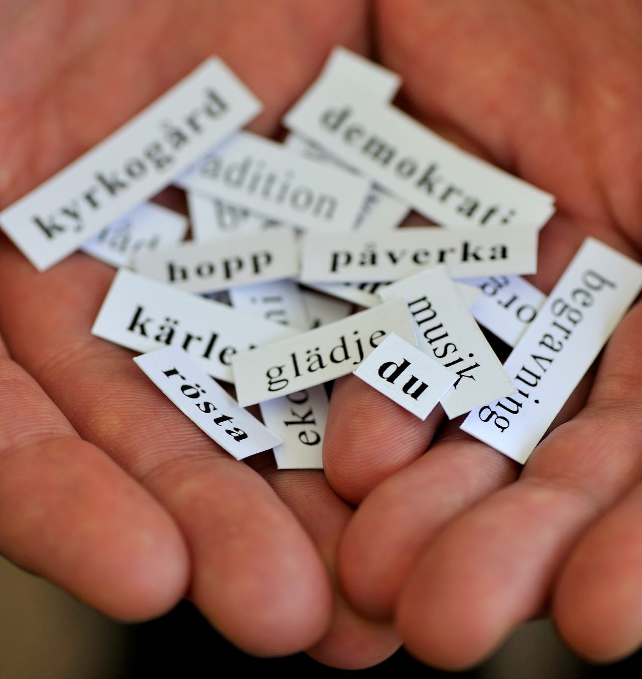 Händer med papperslappar med ord.