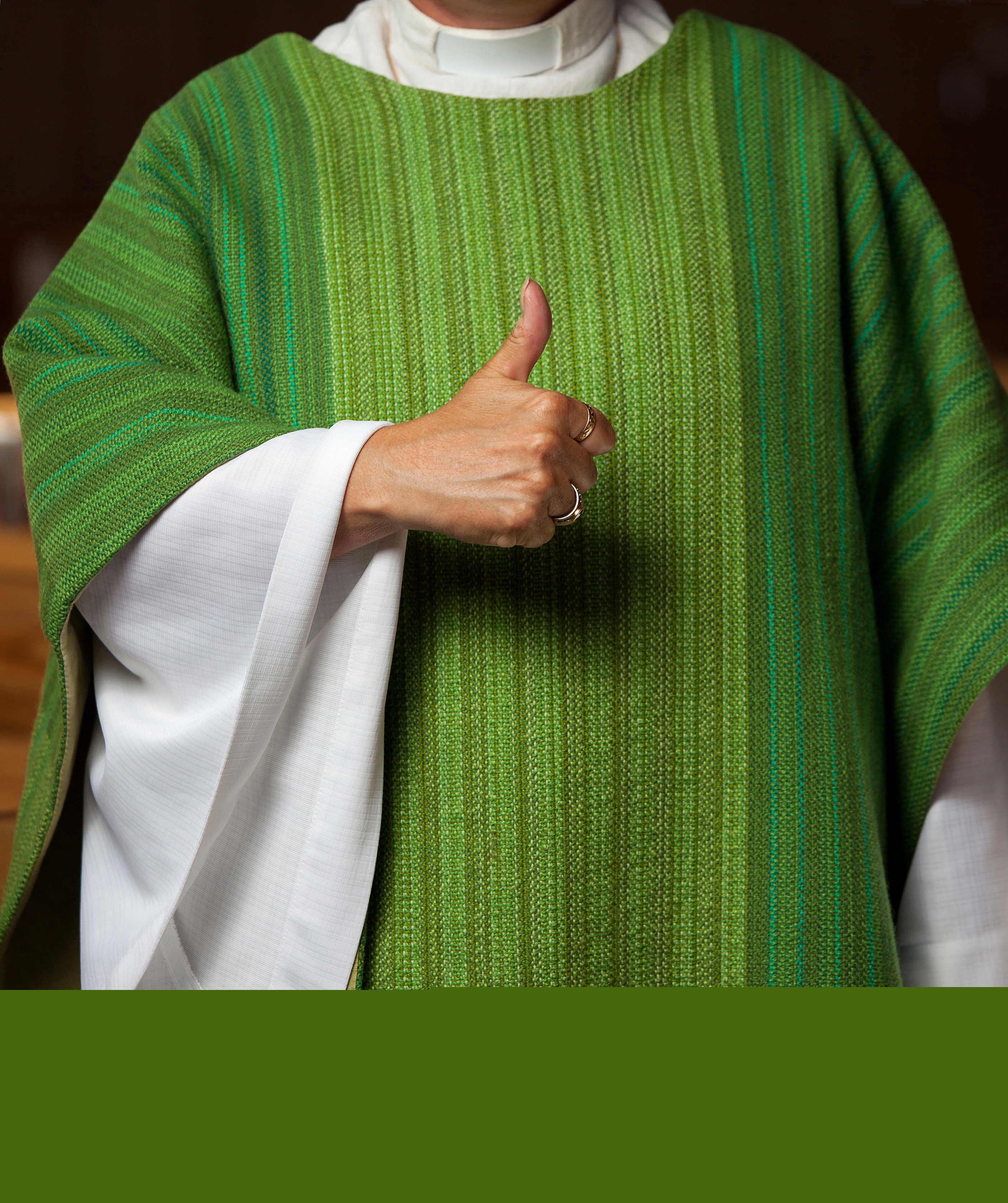 En präst med grön kåpa gör tummen upp mot kameran.