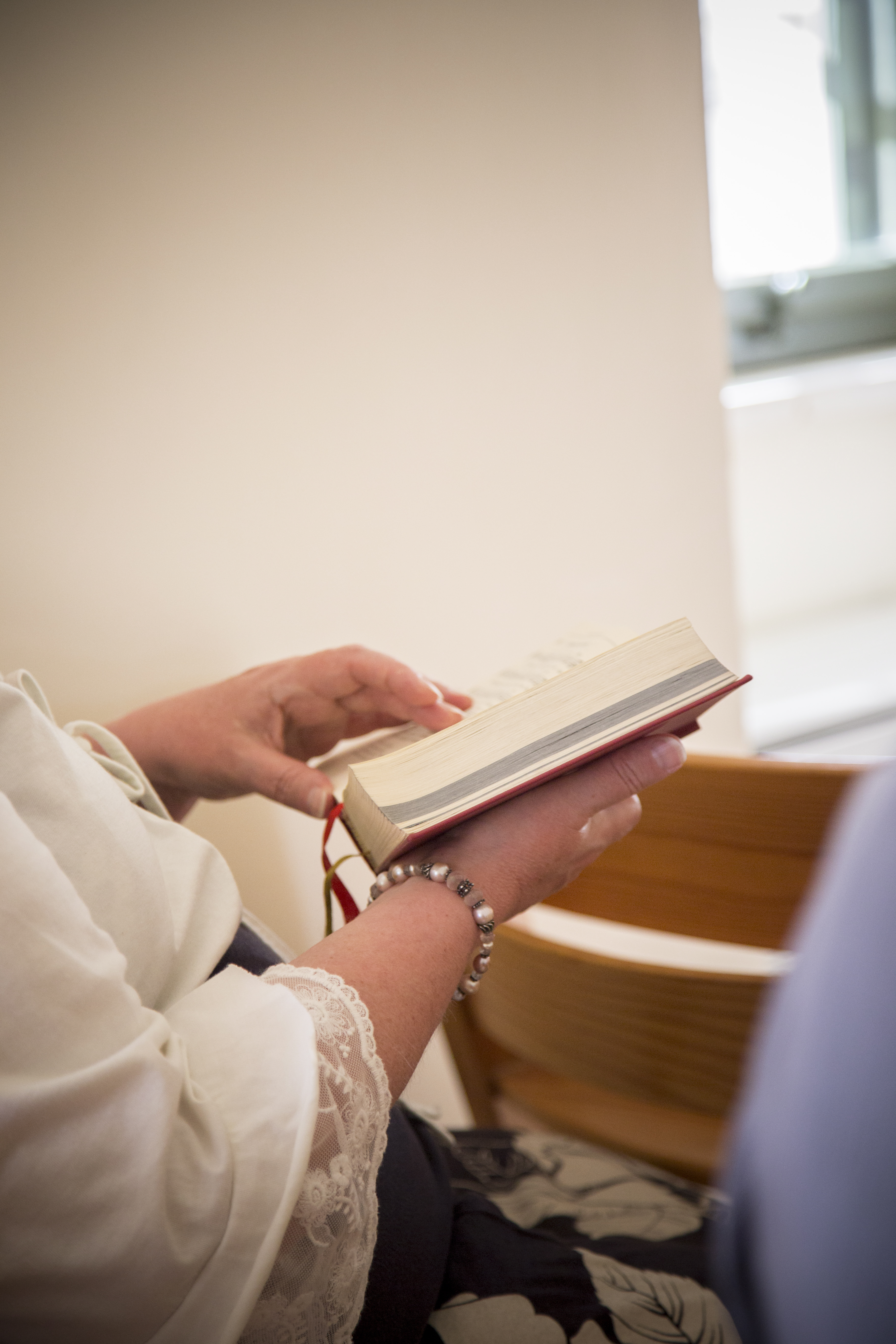 En person sitter och bläddrar i en psalmbok.