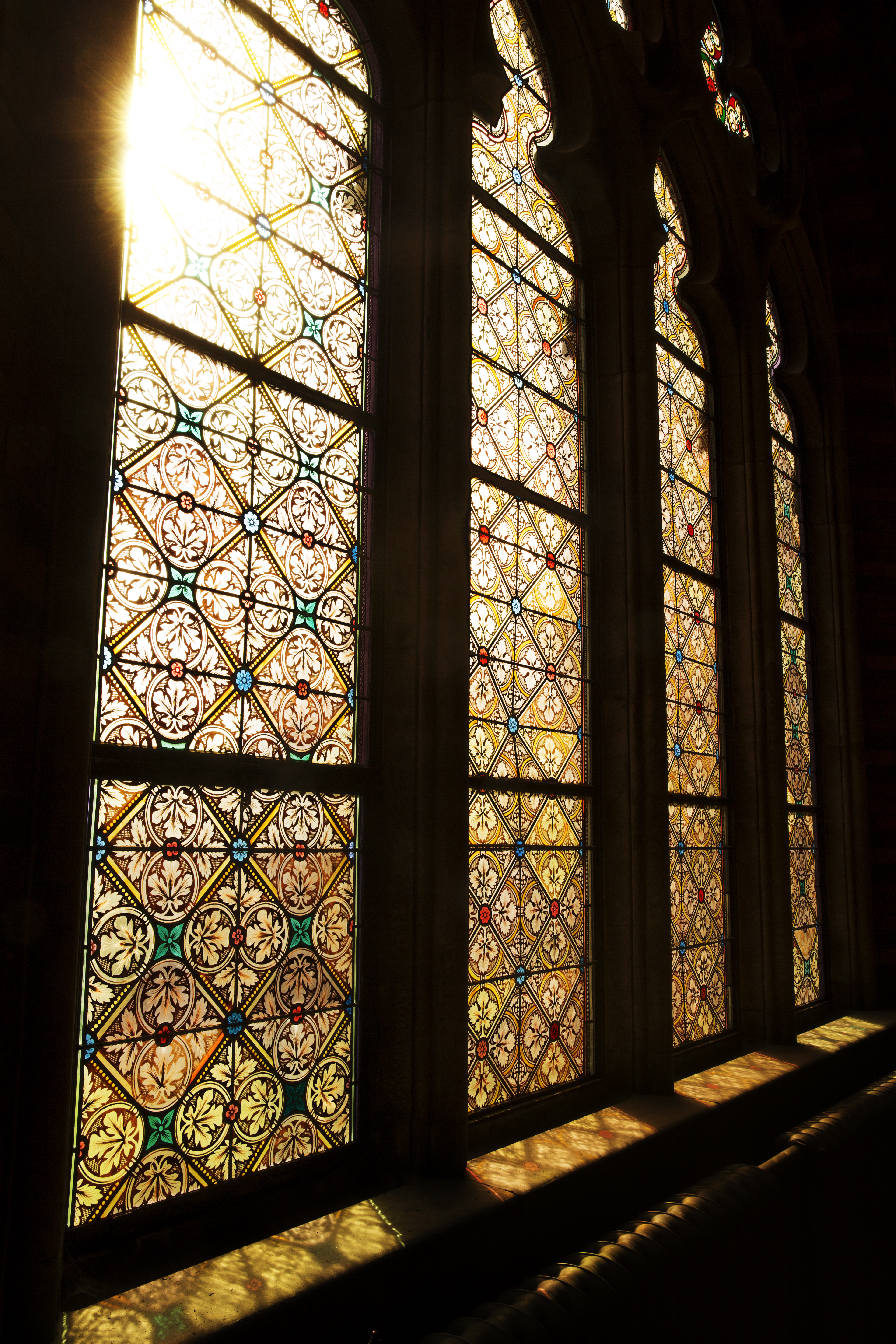 Solen lyser igenom ett färggrant kyrkfönster.