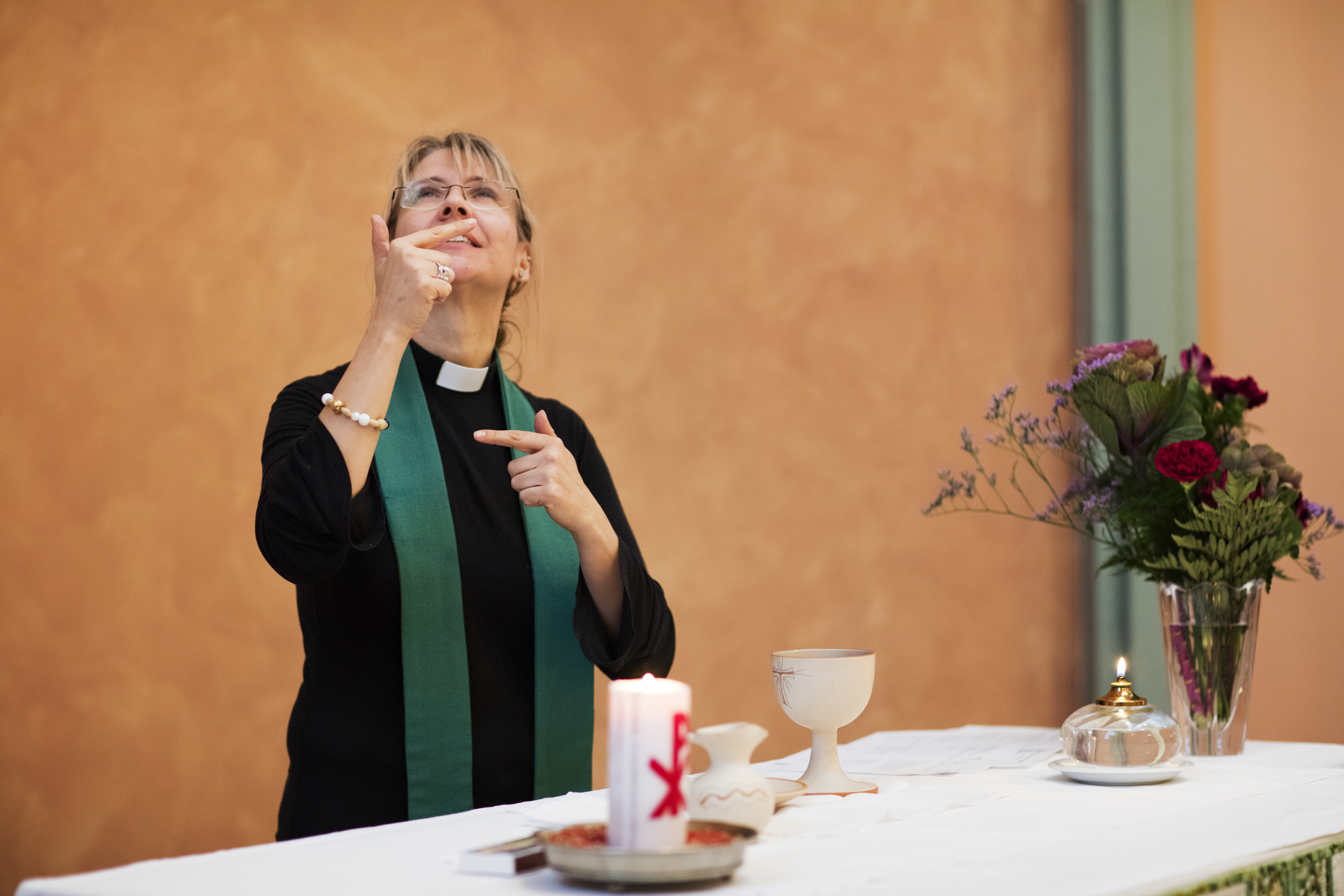 En kvinnlig präst står bakom ett altare.
