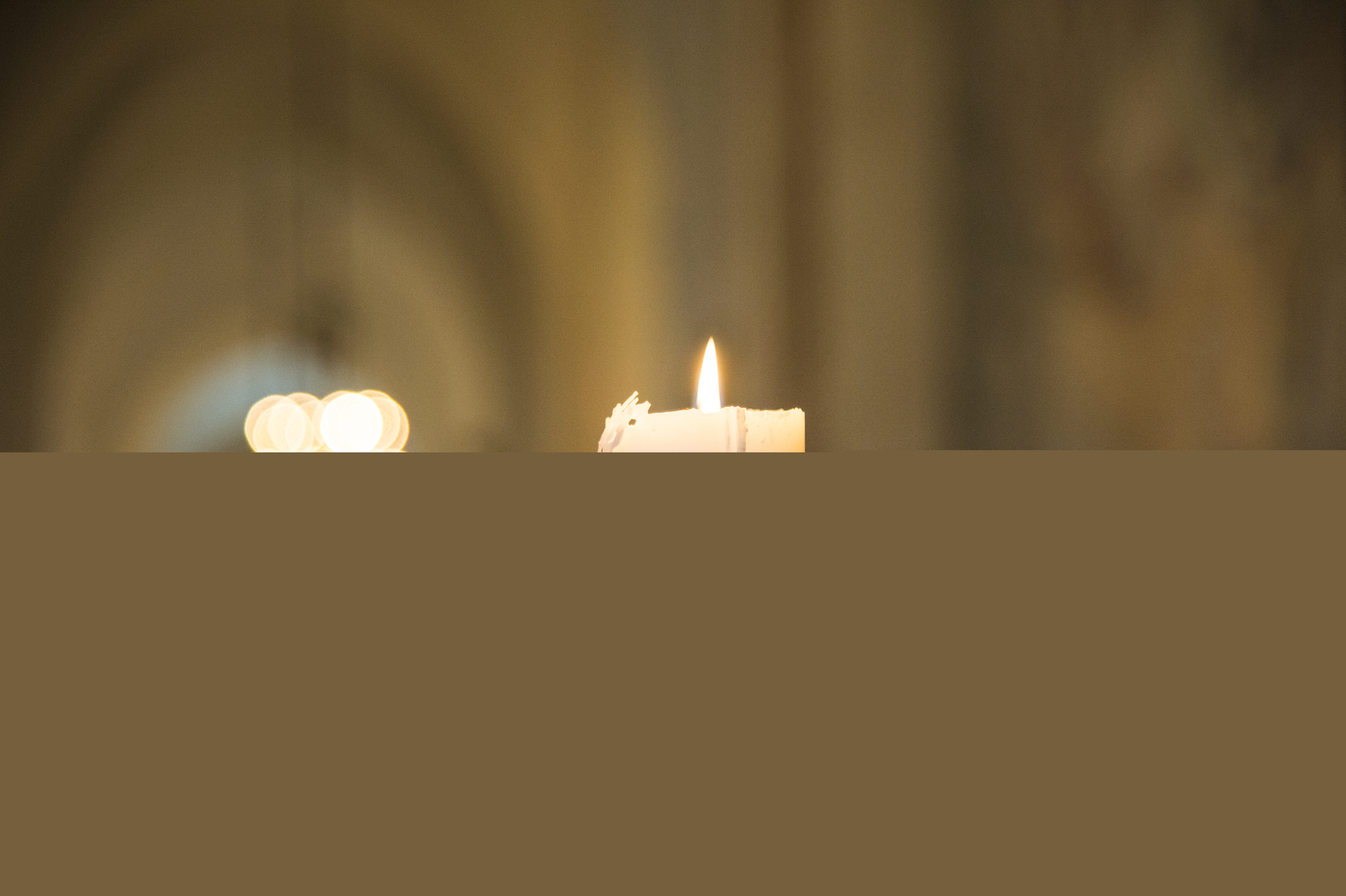 Ett tänt stearinljus i en kyrka.