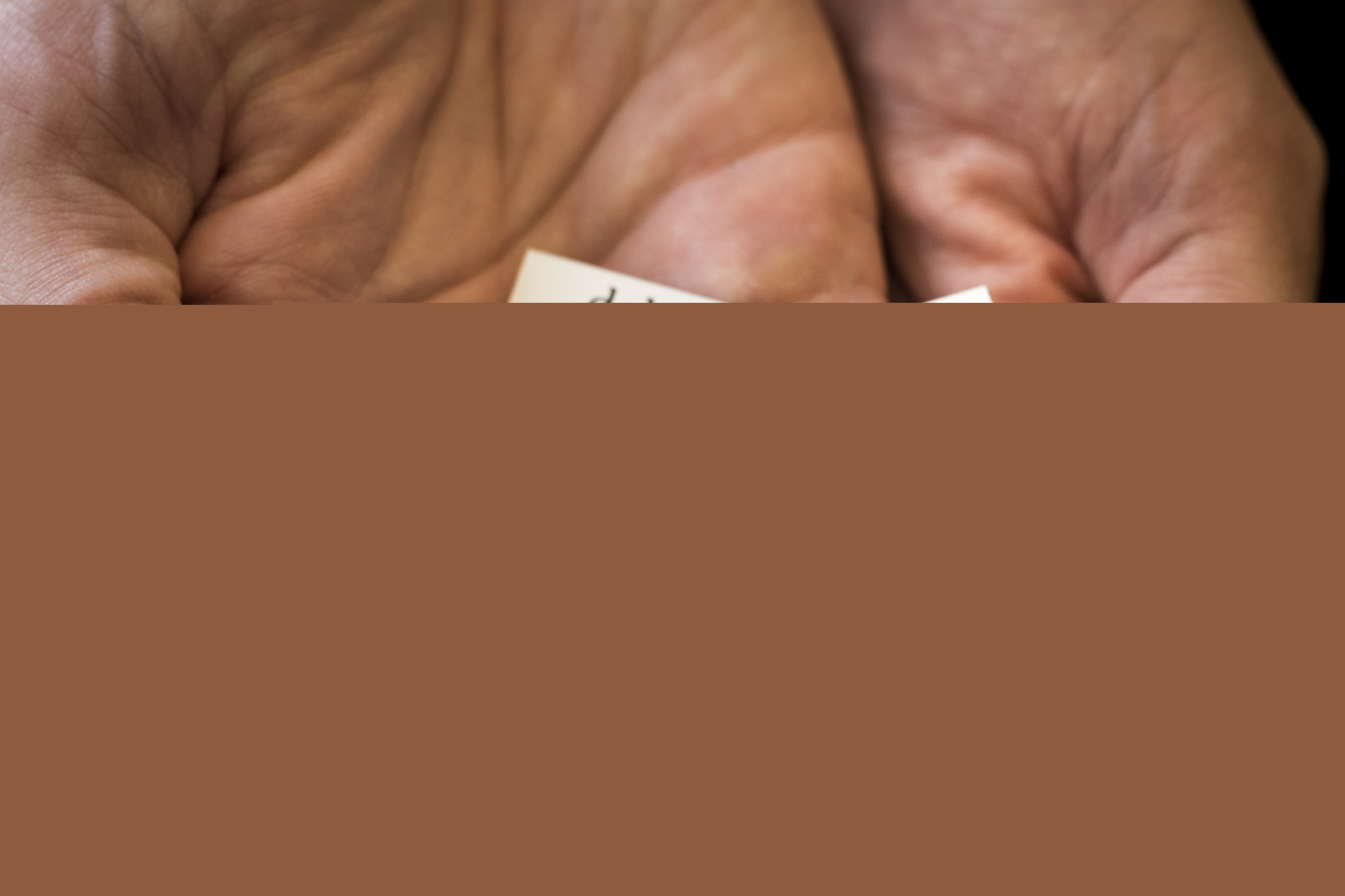 Närbild på någon som håller fram några kylskåpsmagneter med ord som tvivel, livet, Gud, dela, tro och så vidare.