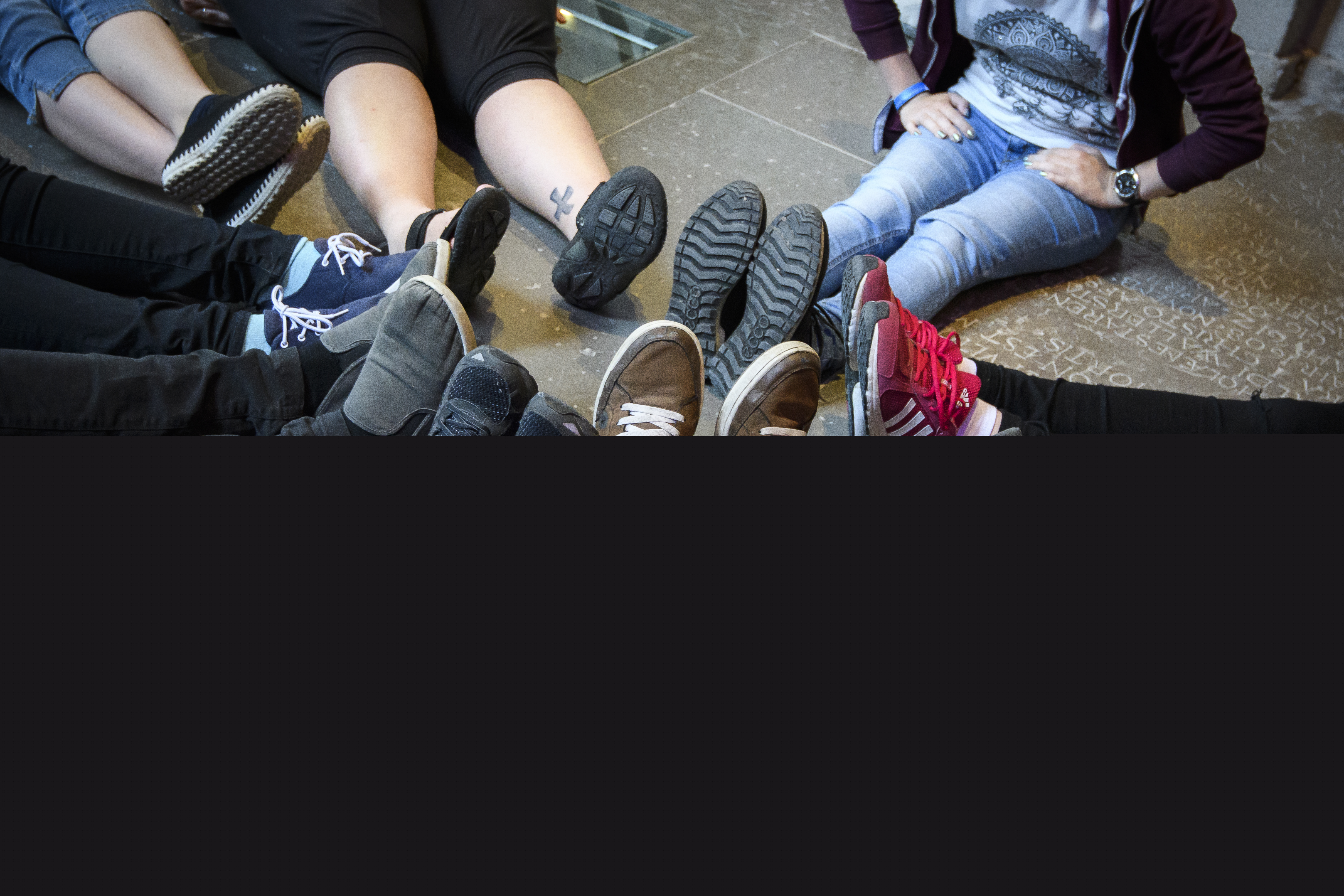 Ungdomar som sitter i en liten ring med fötterna in mot mitten.