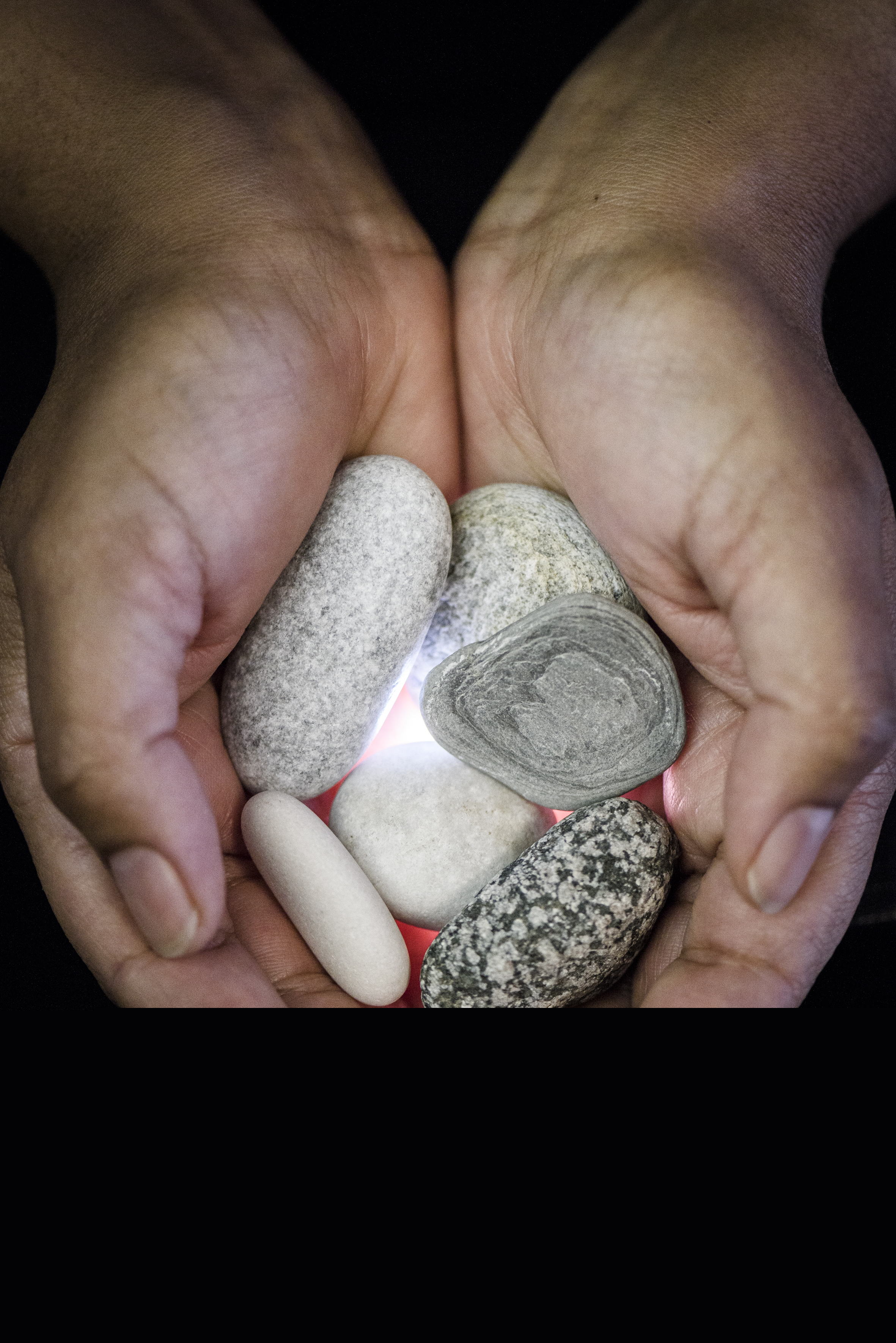 Närbild på en person som håller fram några stenar i handflatorna.
