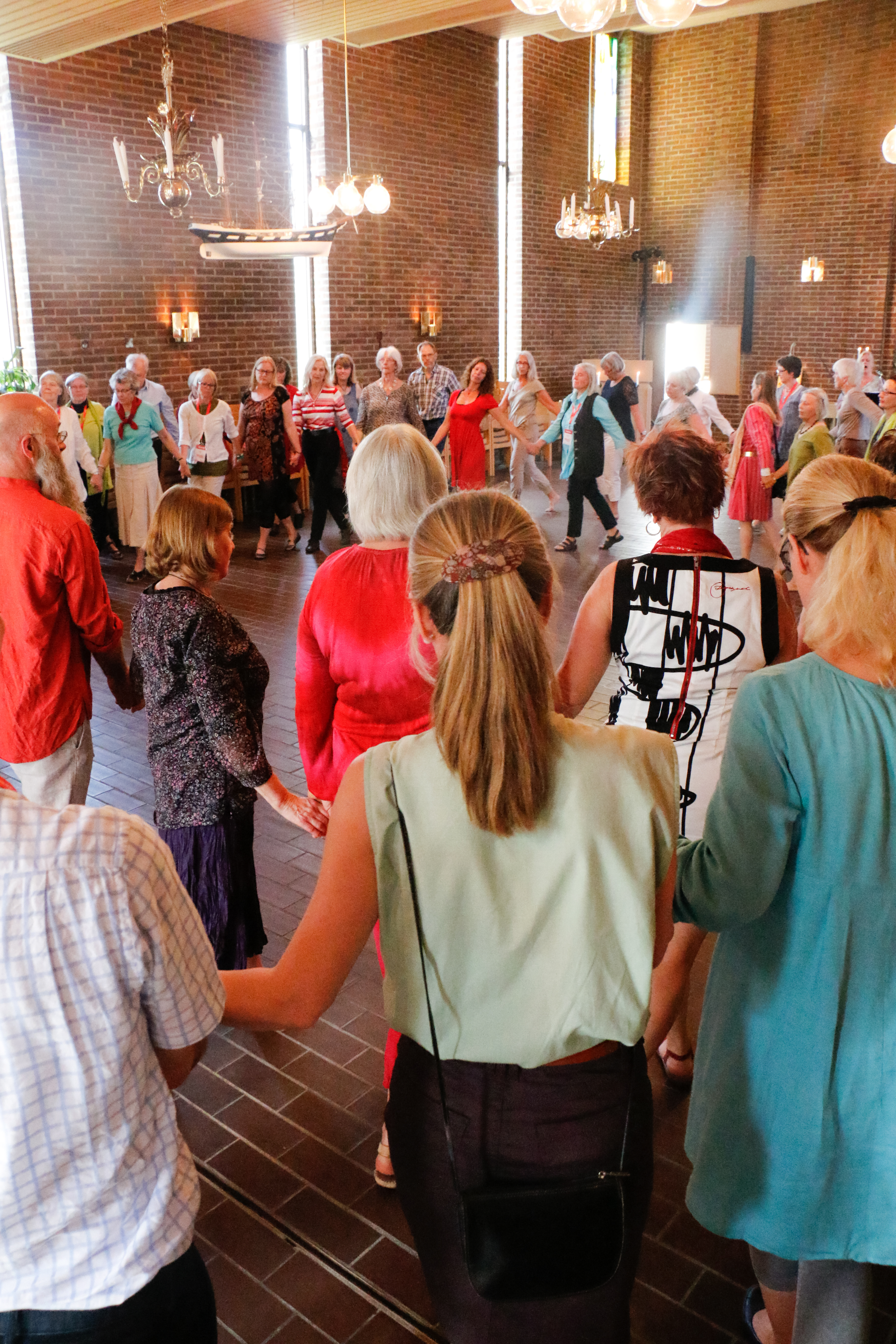 En grupp människor går runt i en stor ring och håller hand.