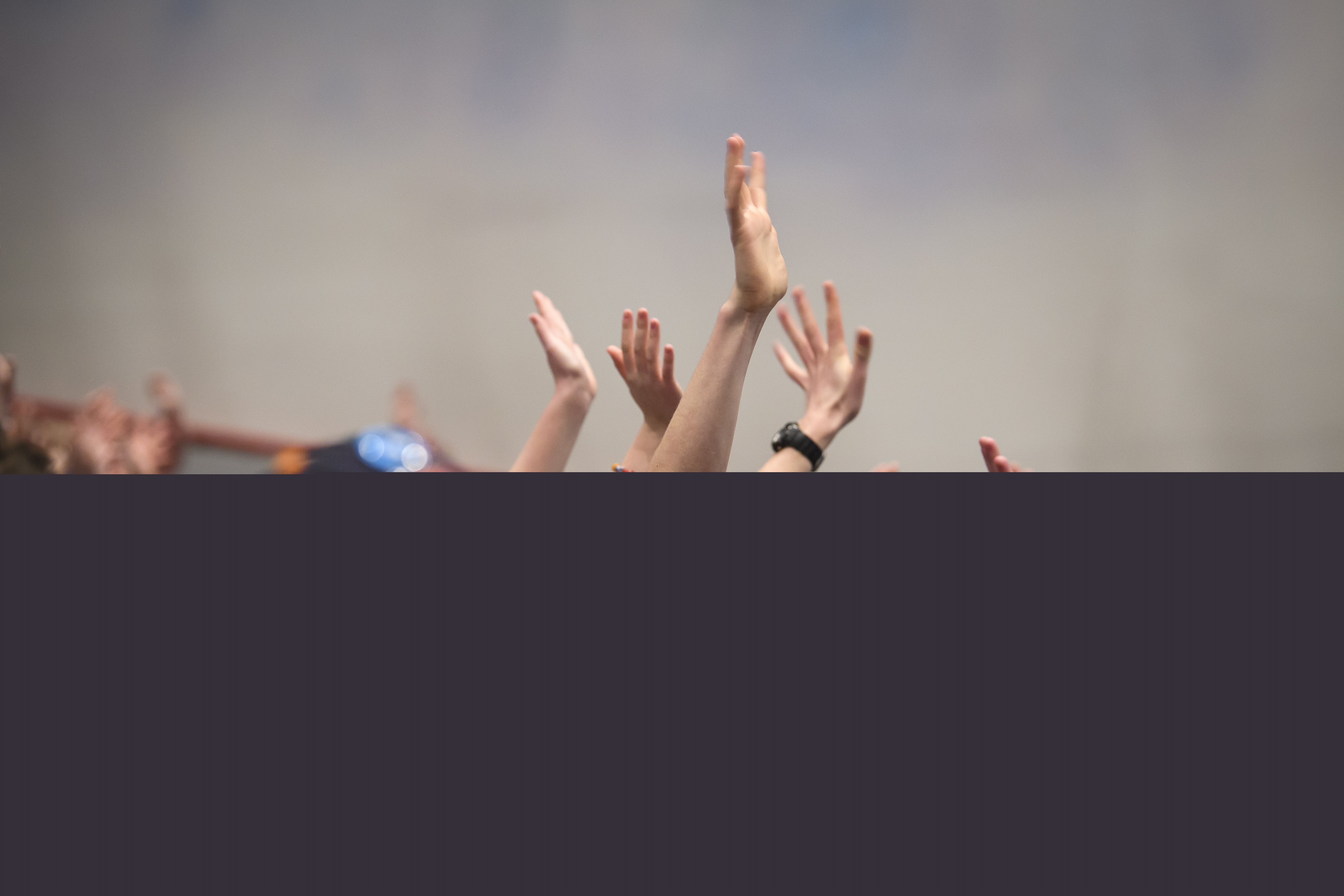 En stor grupp med ungdomar sträcker upp händerna i luften.