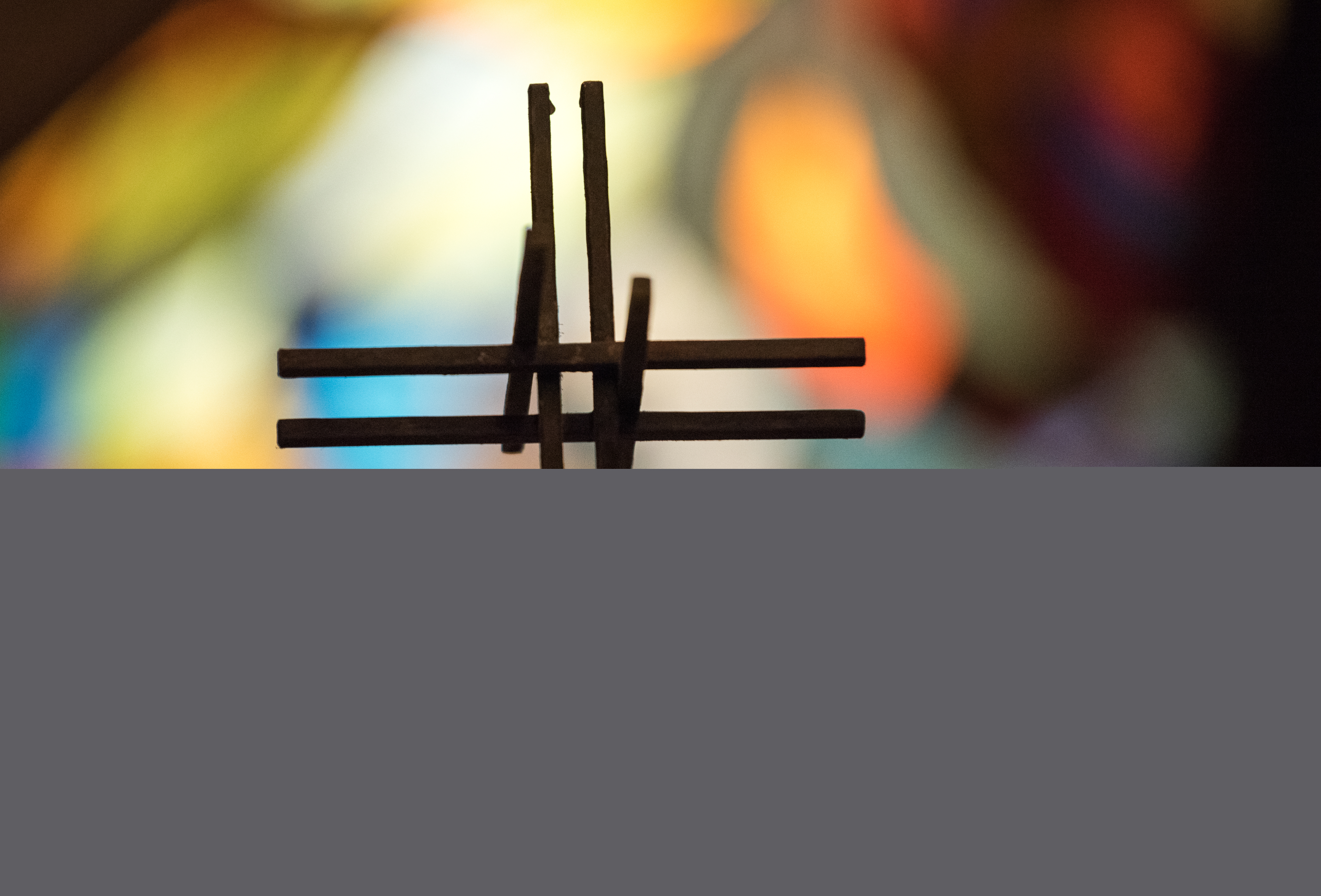 Ett kors i motljus. Suddiga färger syns i bakgrunden.