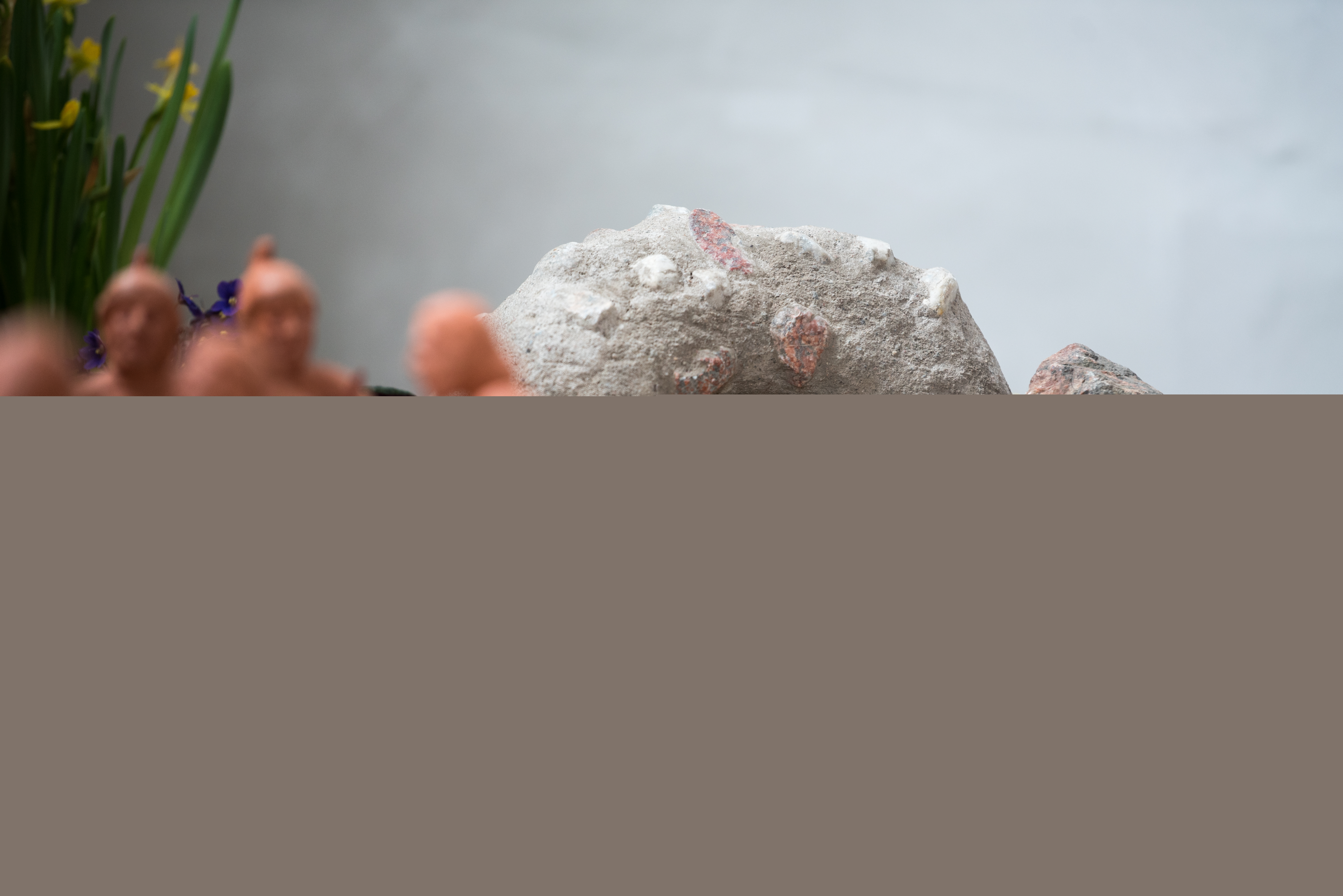 En grupp med små lerfigurer står framför en miniatyrgrotta av sten.