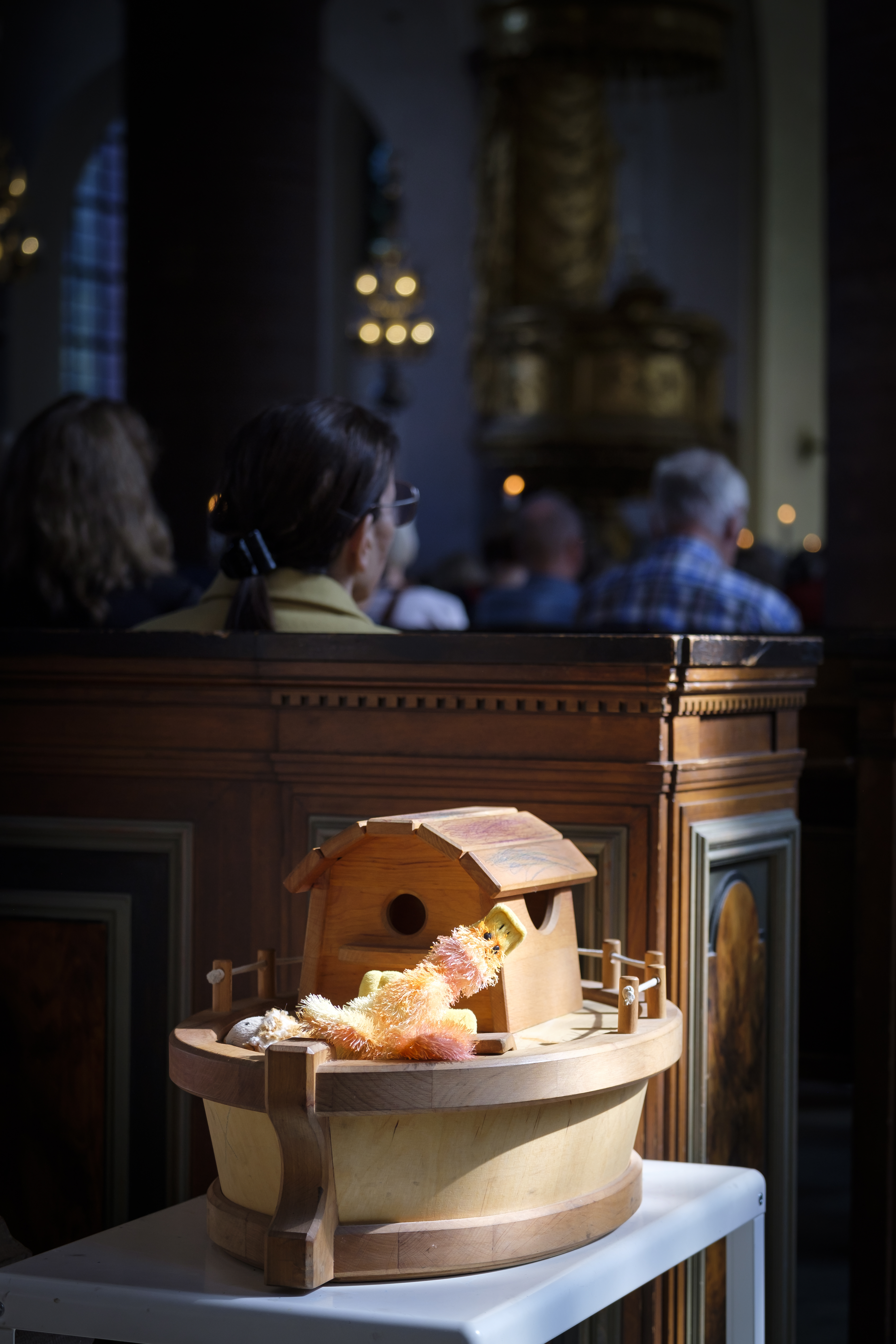 En miniatyr av Noas ark står i en kyrka. Fulla kyrkbänkar i bakgrunden.