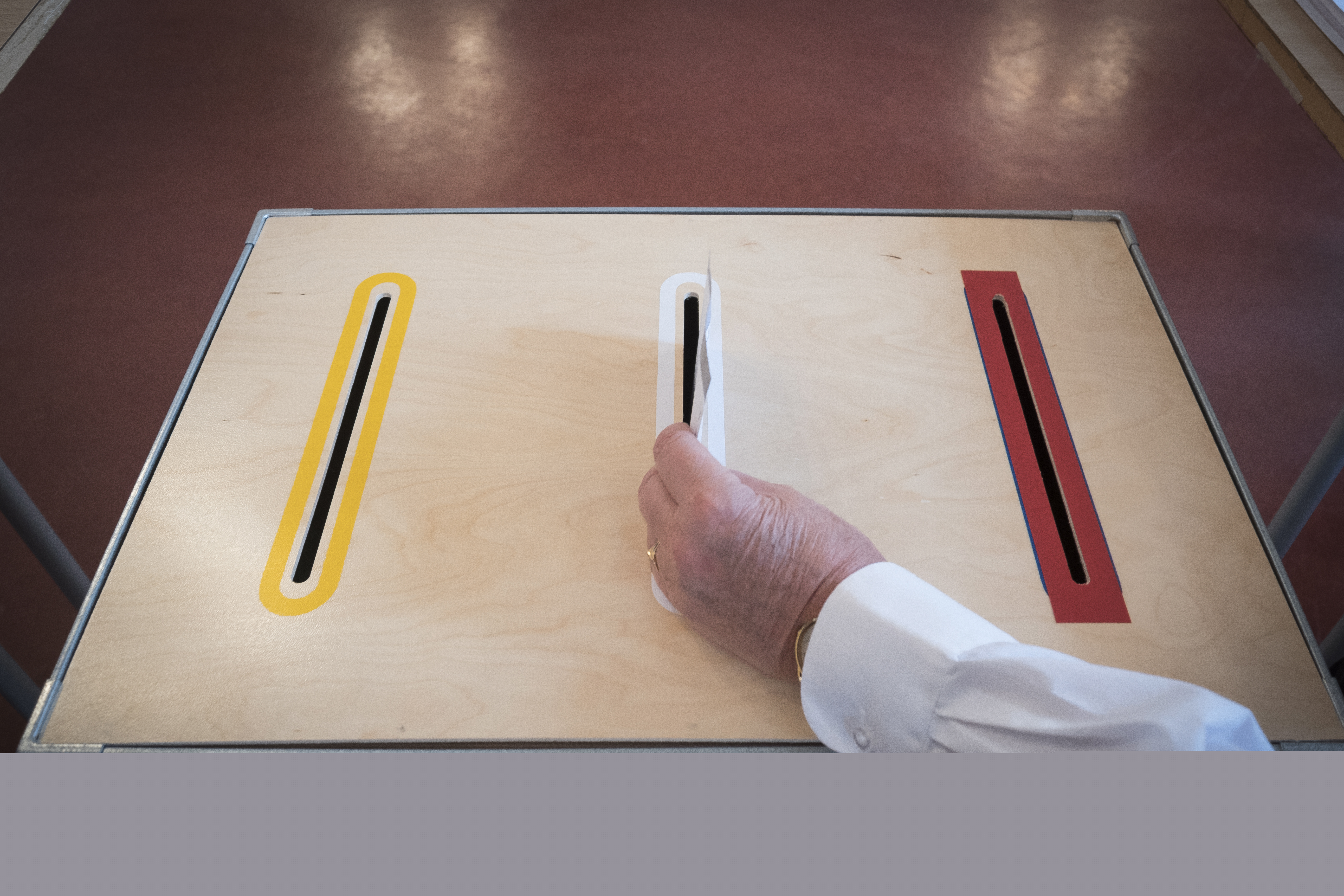 Någon stoppar ett valkuvert i en valurna.