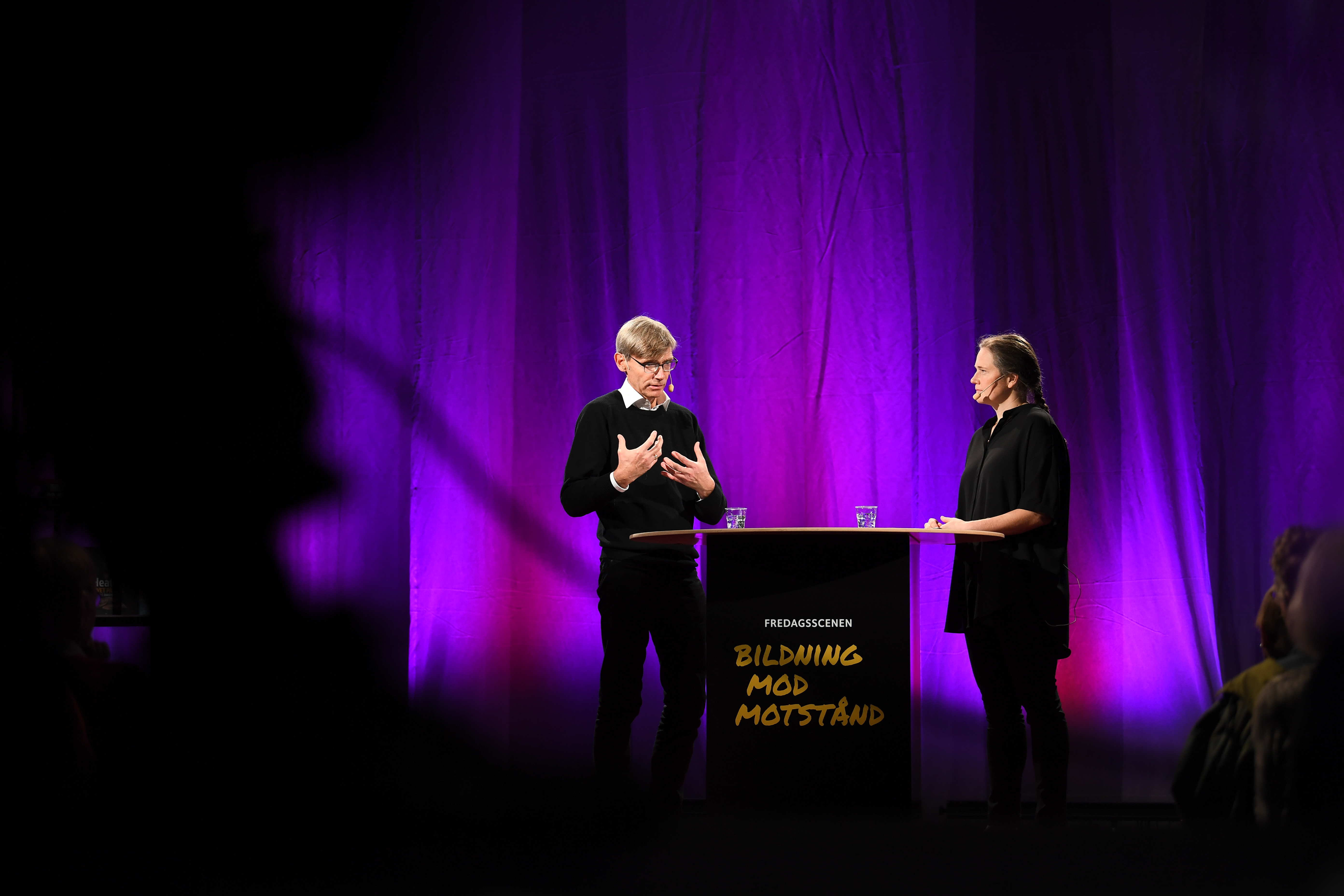 På en upplyst scen pågår ett samtal på temat Bildning Mod Motstånd.