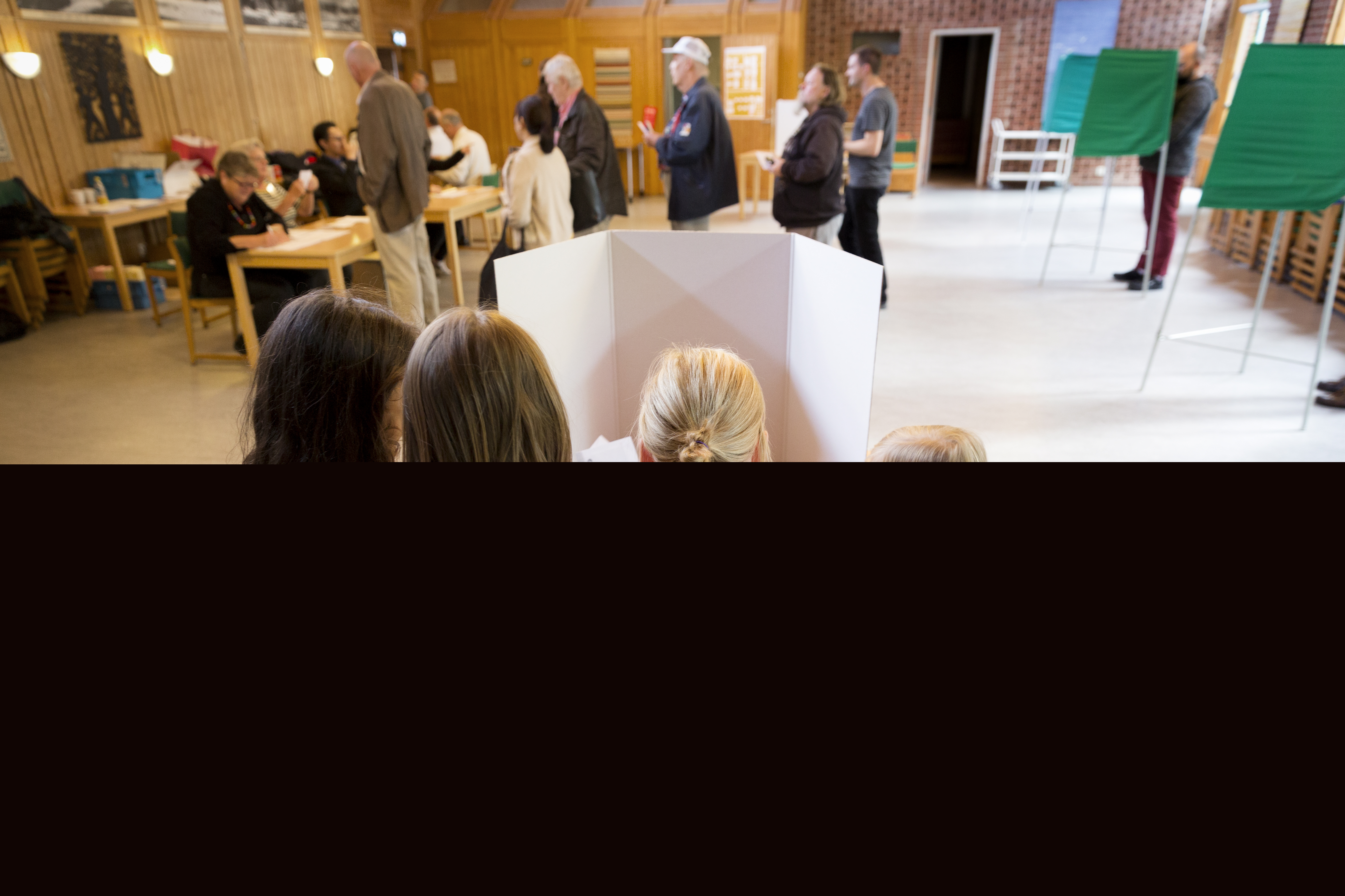 Tre små flickor står runt sin mamma i ett röstbås.