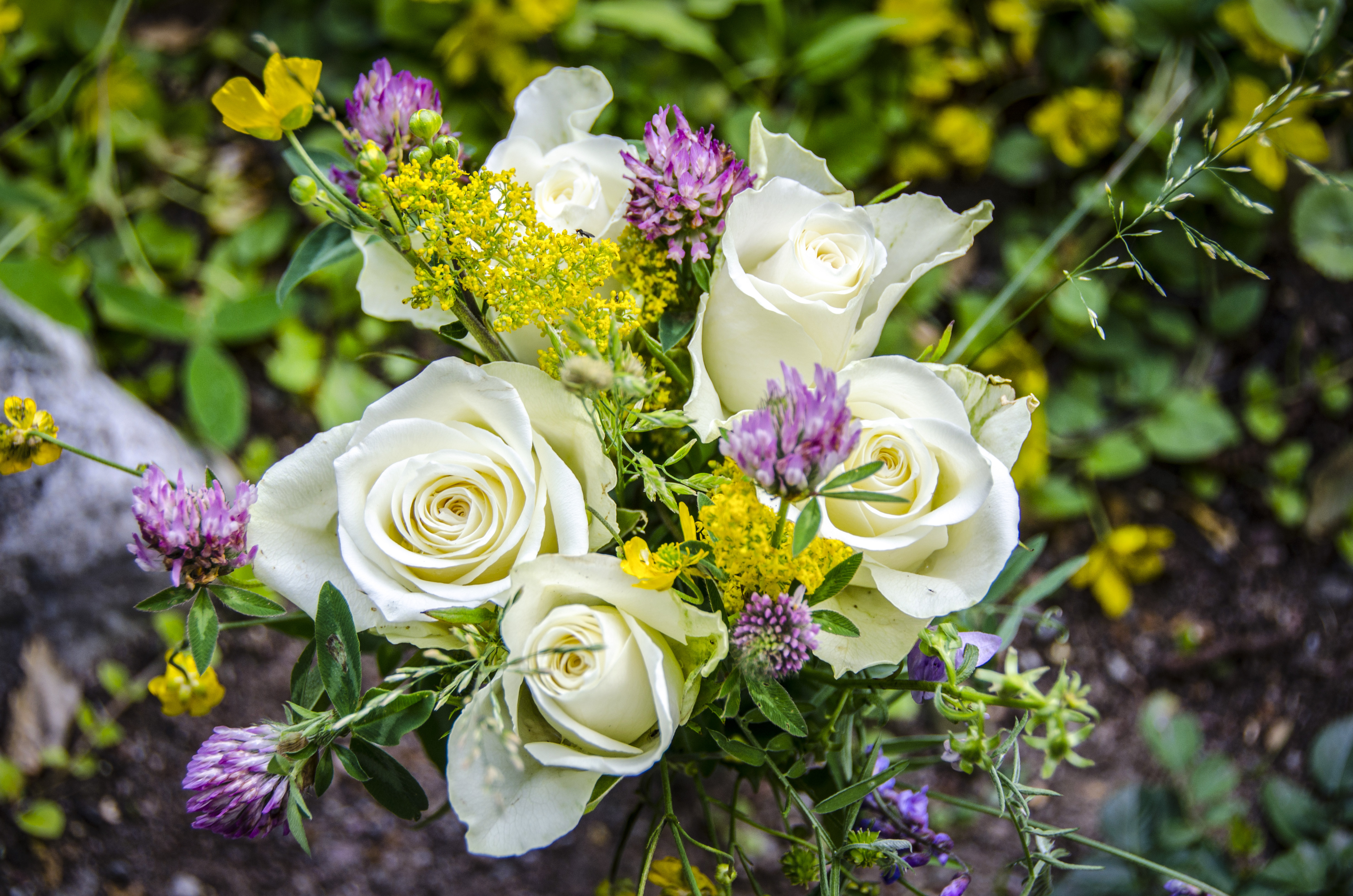 En bukett med vita rosor och vilda blommor.