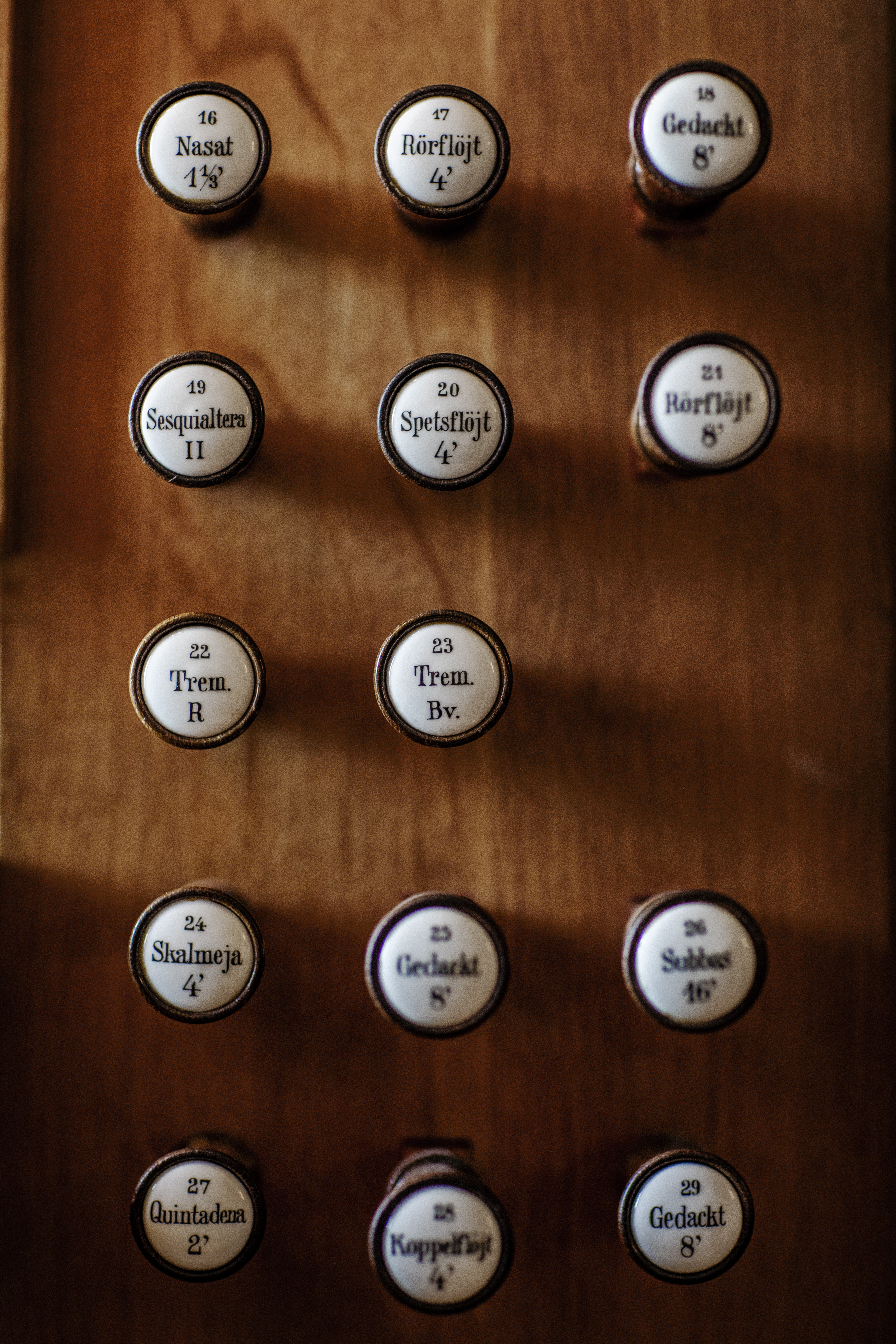 Närbild på en kyrkorgels registerandrag, de runda vita spakarna på sidorna av klaviaturen.