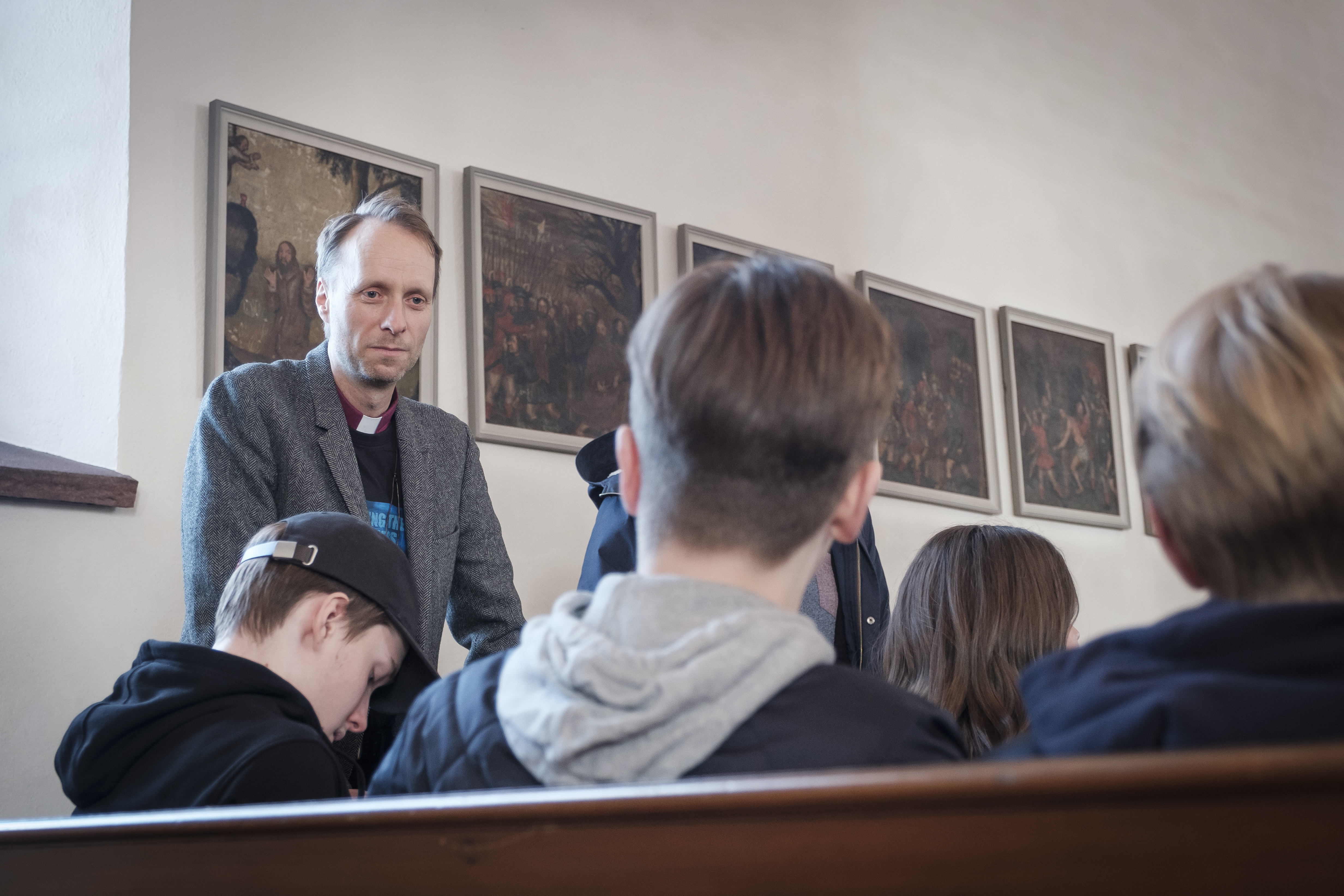 Biskop Mikael Mogren står vid några ungdomar som sitter i kyrkbänkarna.