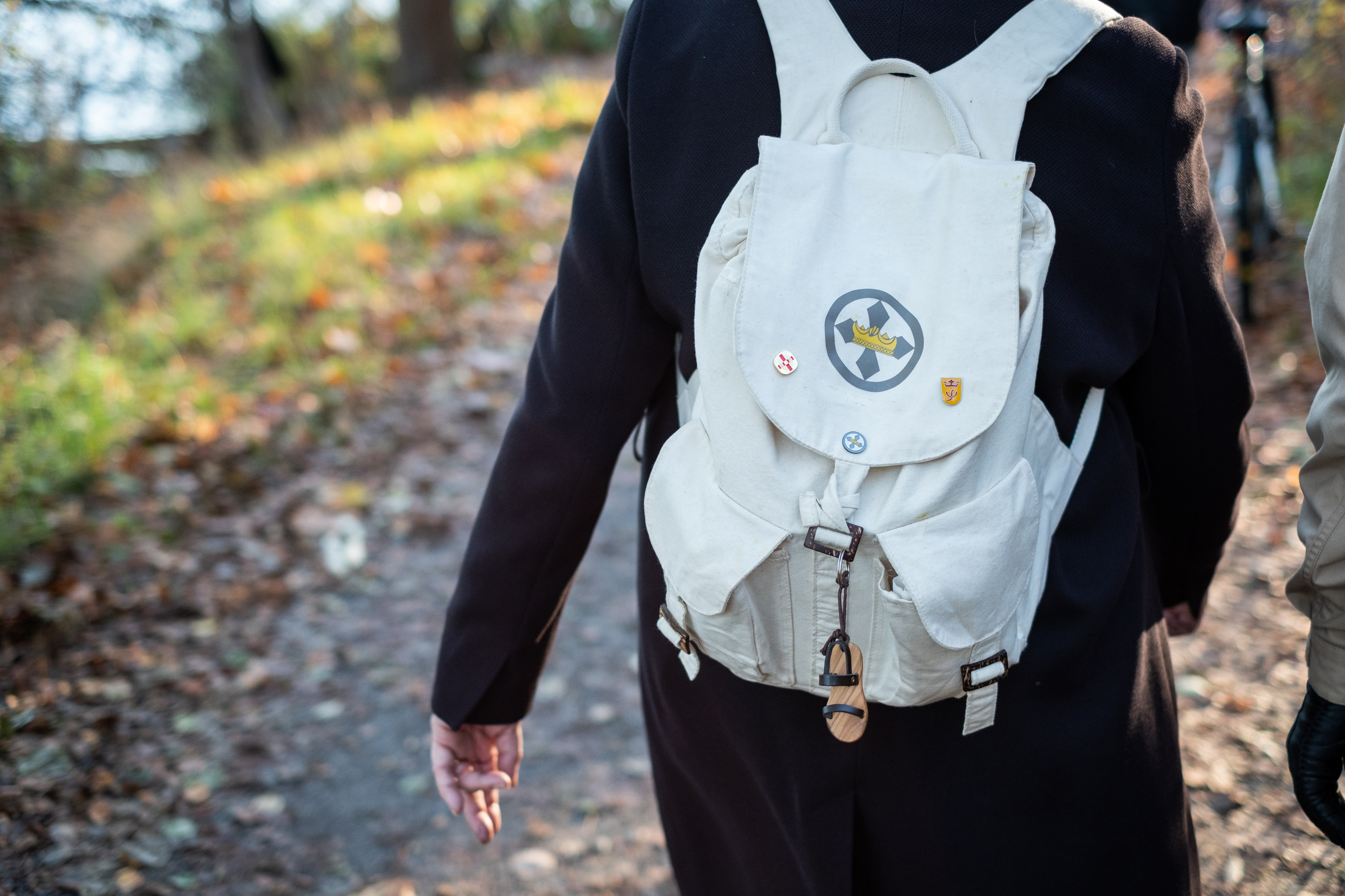 En person med en vit ryggsäck går utomhus en höstdag.