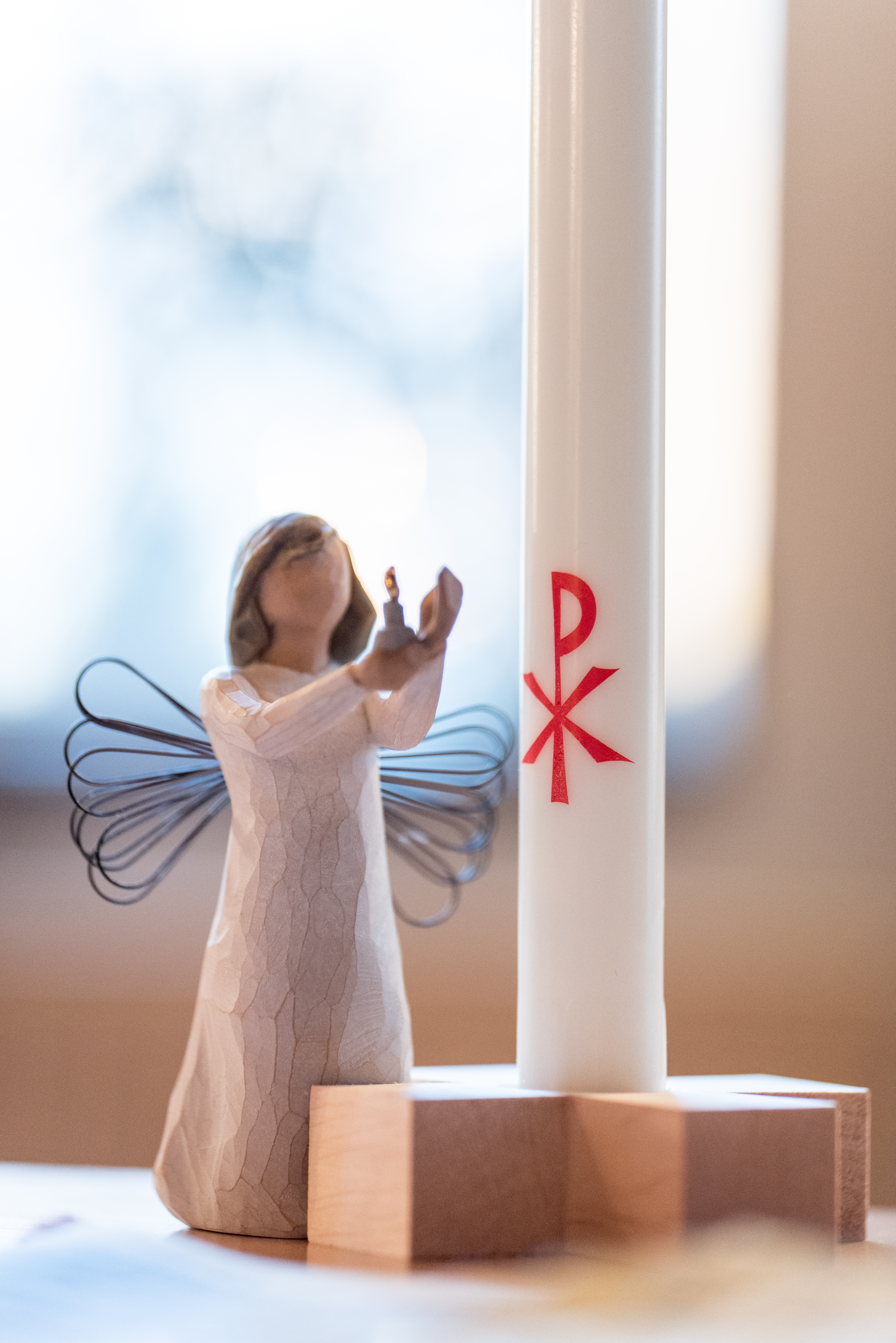 En prydnadsängel står bredvid ett dopljus.