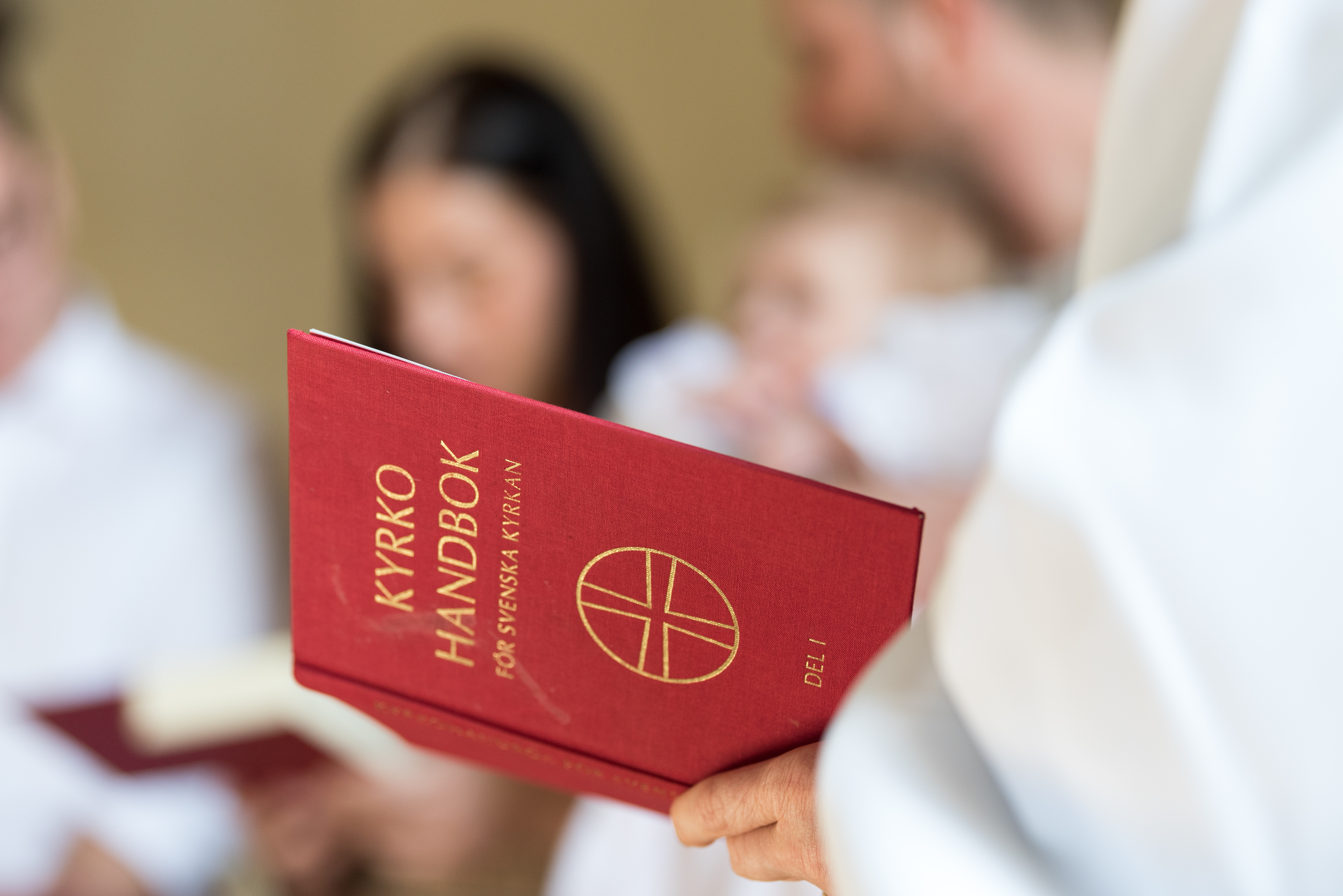 En vitklädd person håller i en kyrkohandbok.