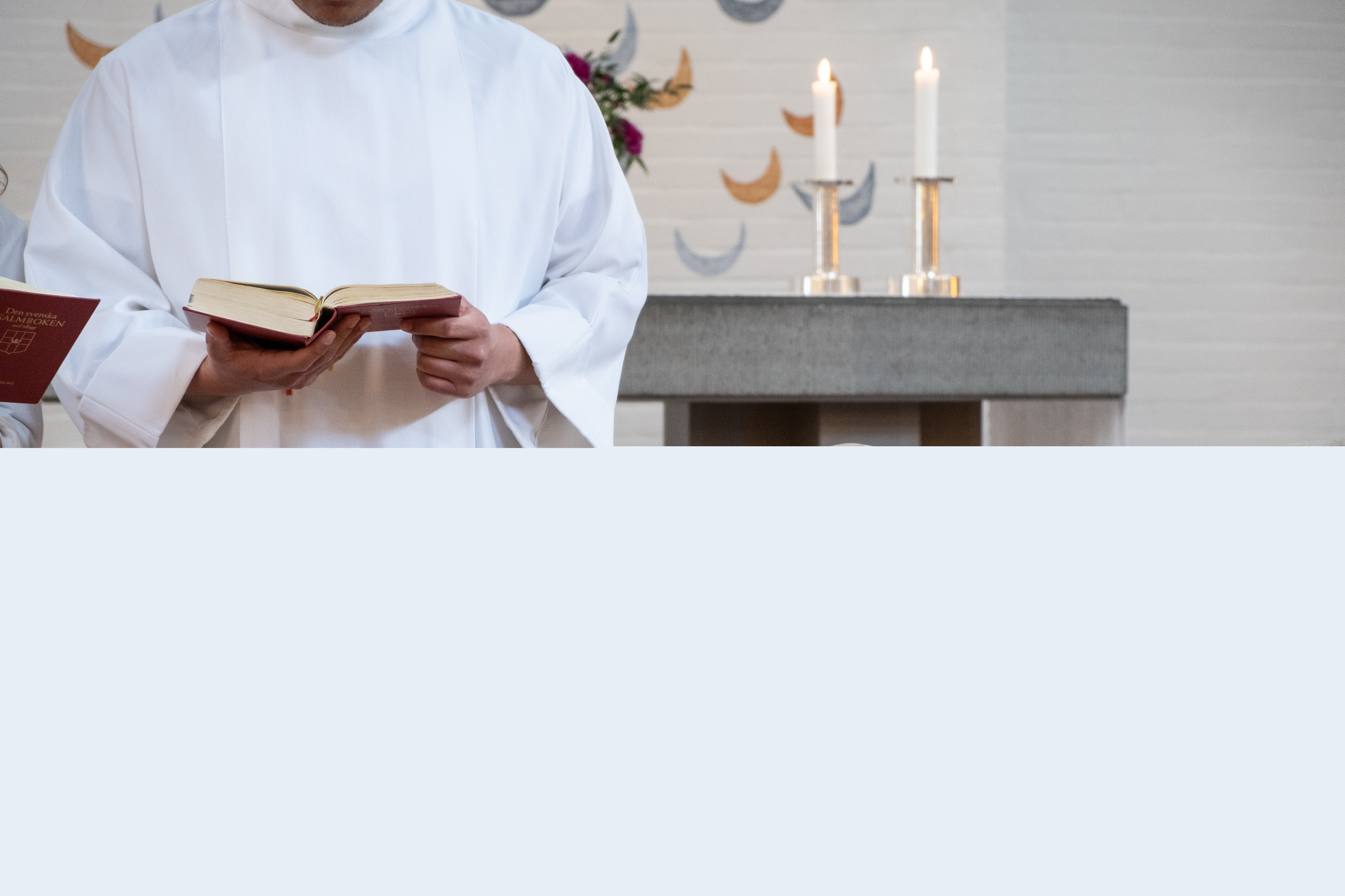 En man i vit kåpa står vid en dopfunt.