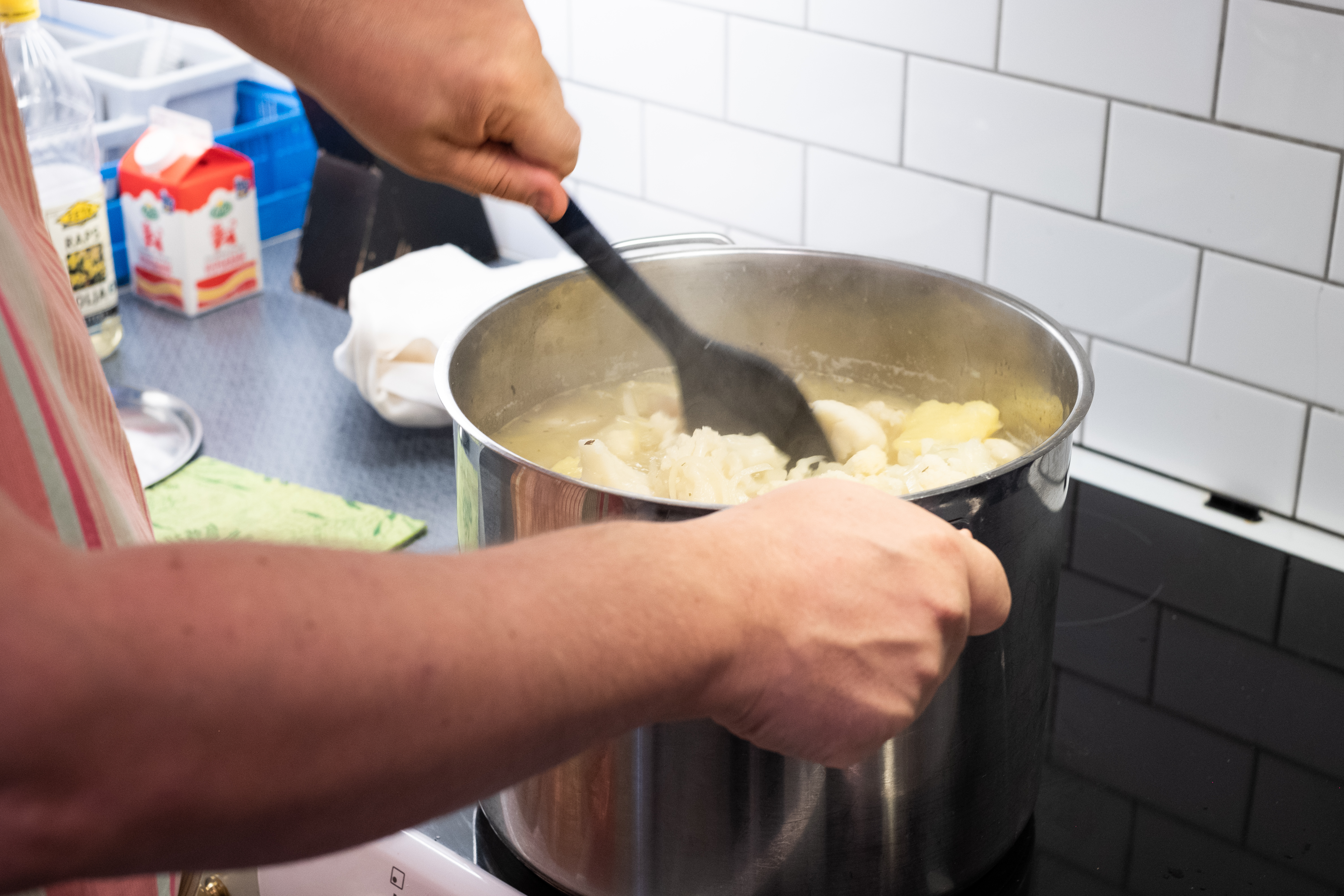 Någon rör om i en stor kastrull på spisen.