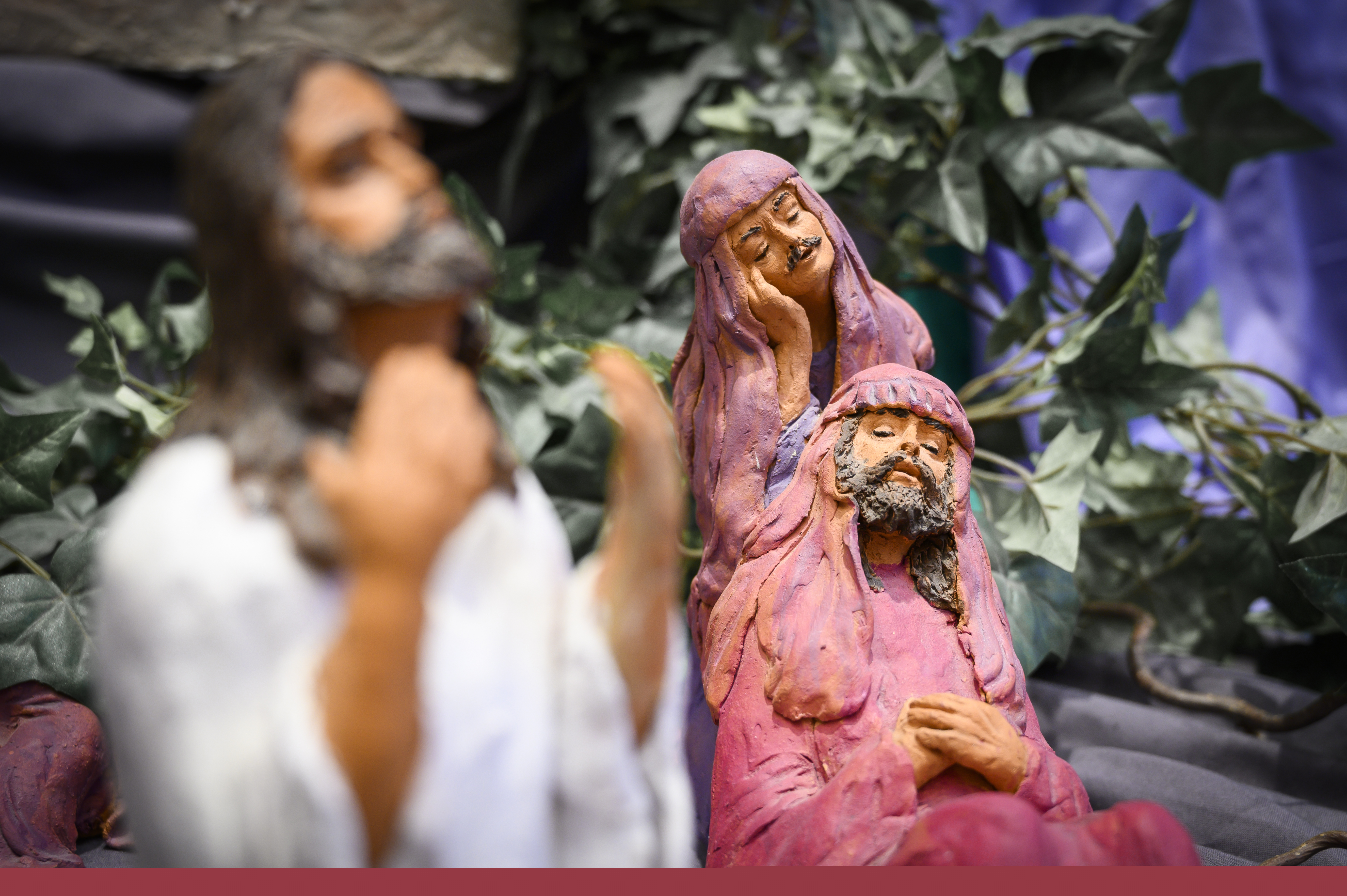 Modell med Jesus och två män i ljusröda kåpor och huvuddukar.