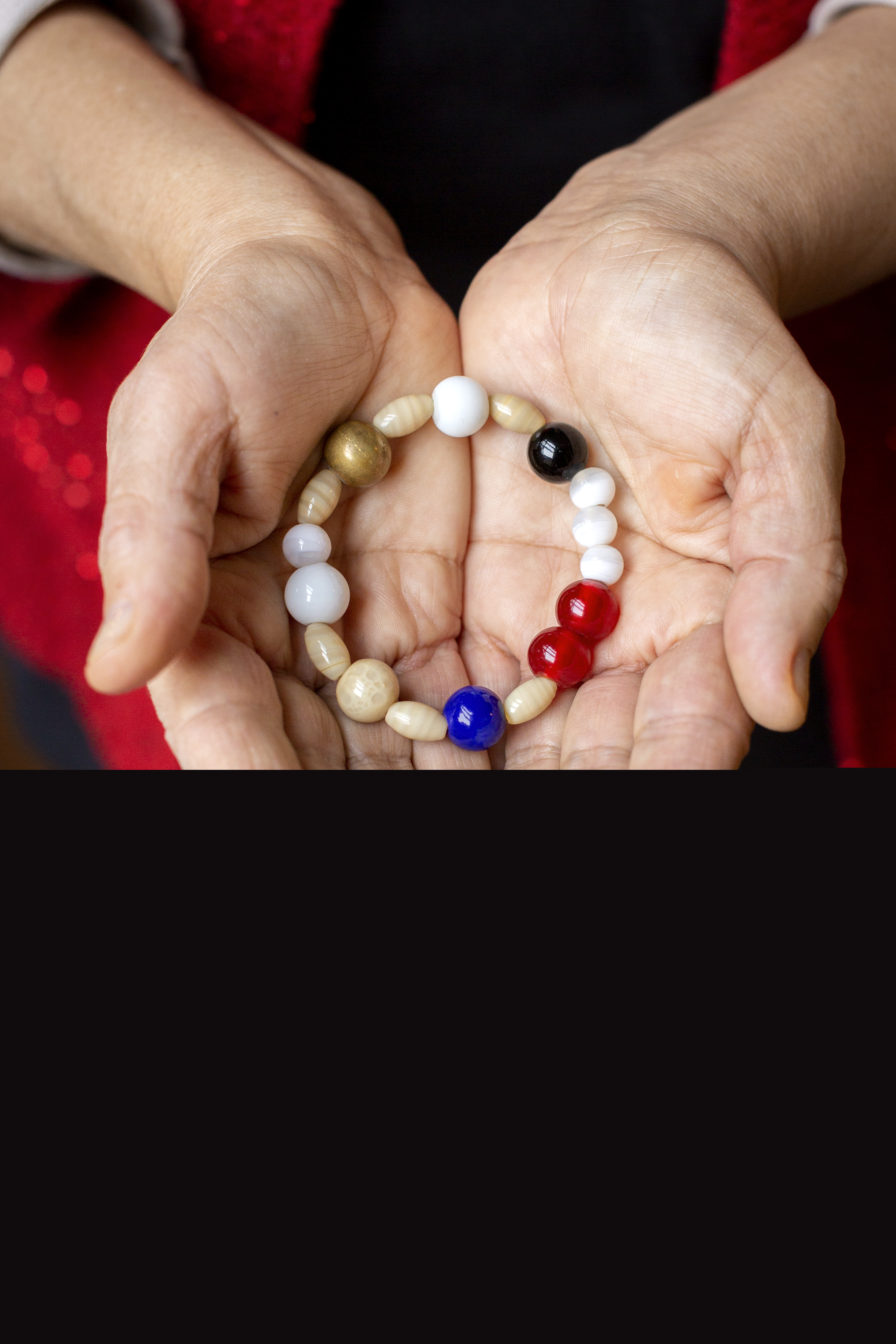 En person håller ett armband av olika pärlor i sina kupade händer.