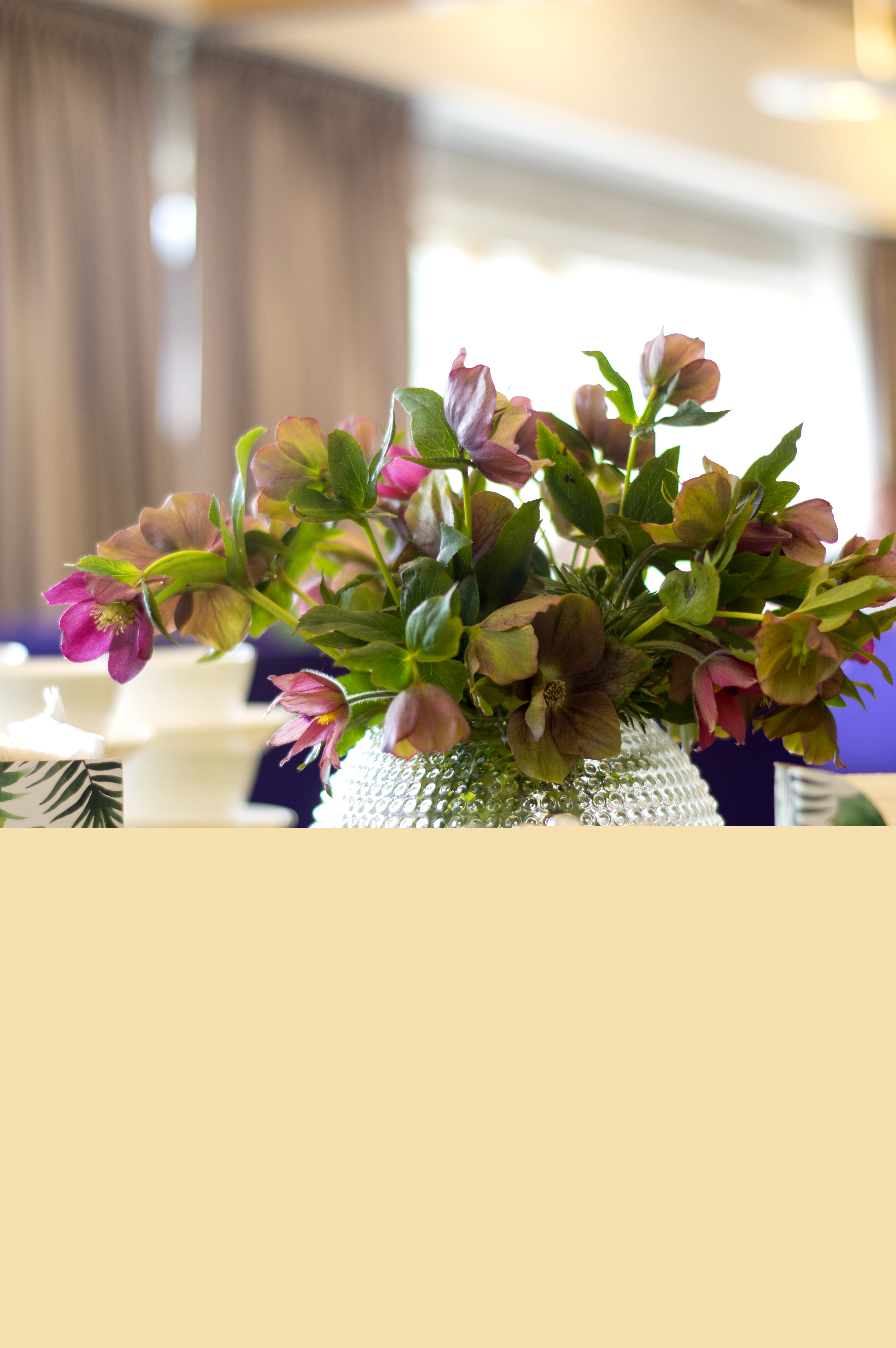 En rosa blombukett står i en vas på ett bord med några tallrikar och bestick.