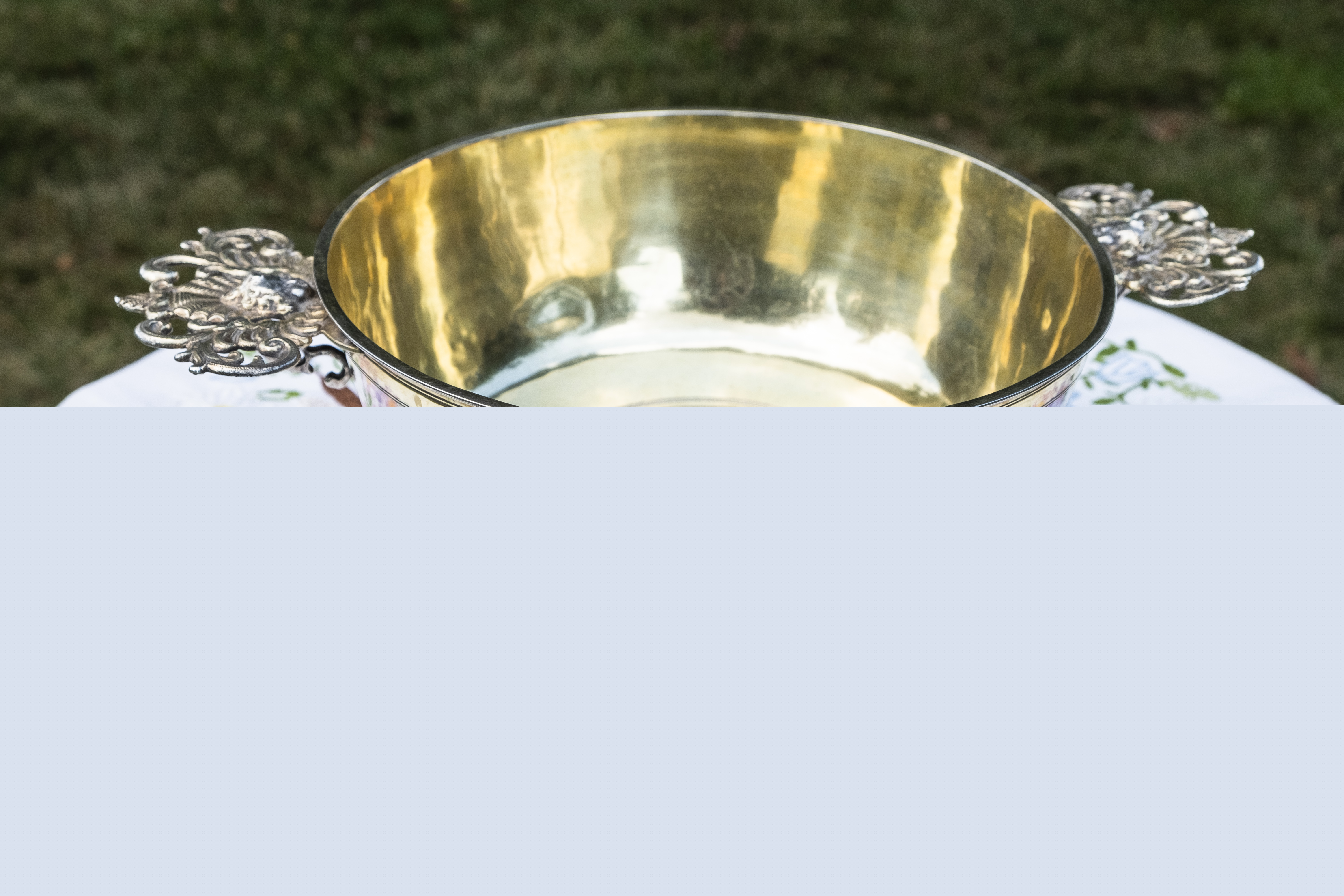 En dopfunt står utomhus på ett bord med en broderad duk.