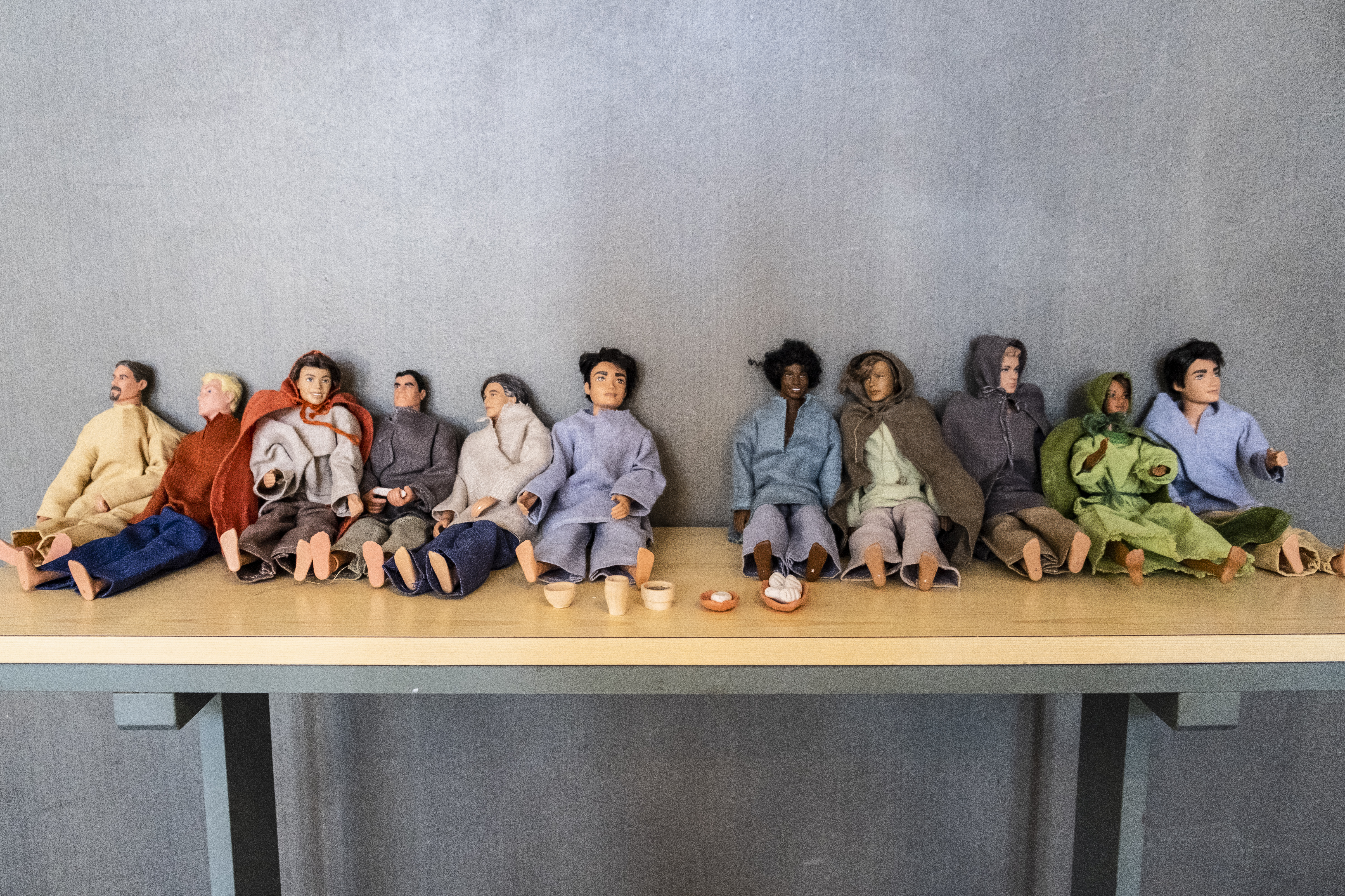 Ett tiotal dockor sitter uppställda på ett litet bord.