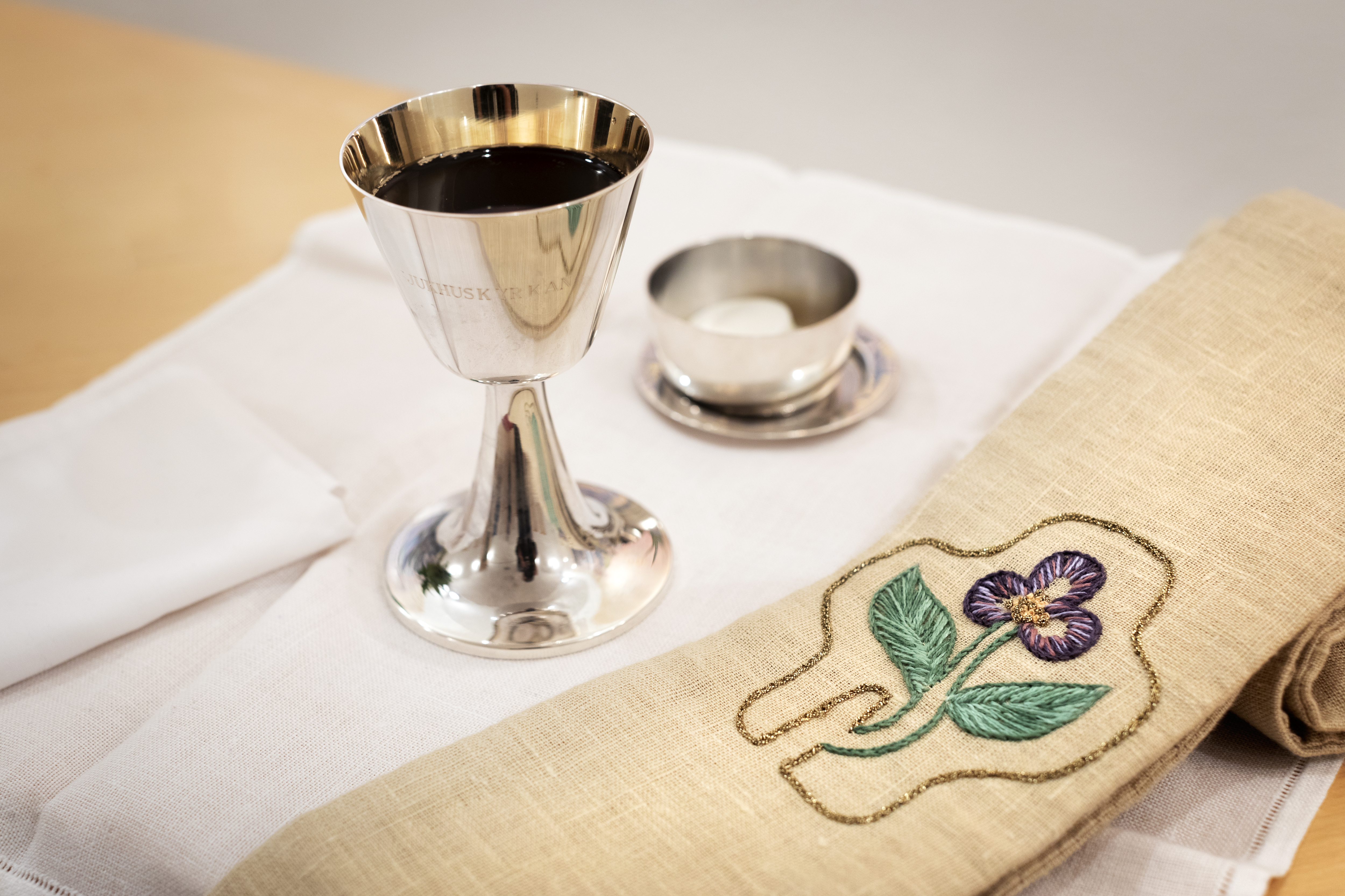 En silverkalk med vin står på ett bord.