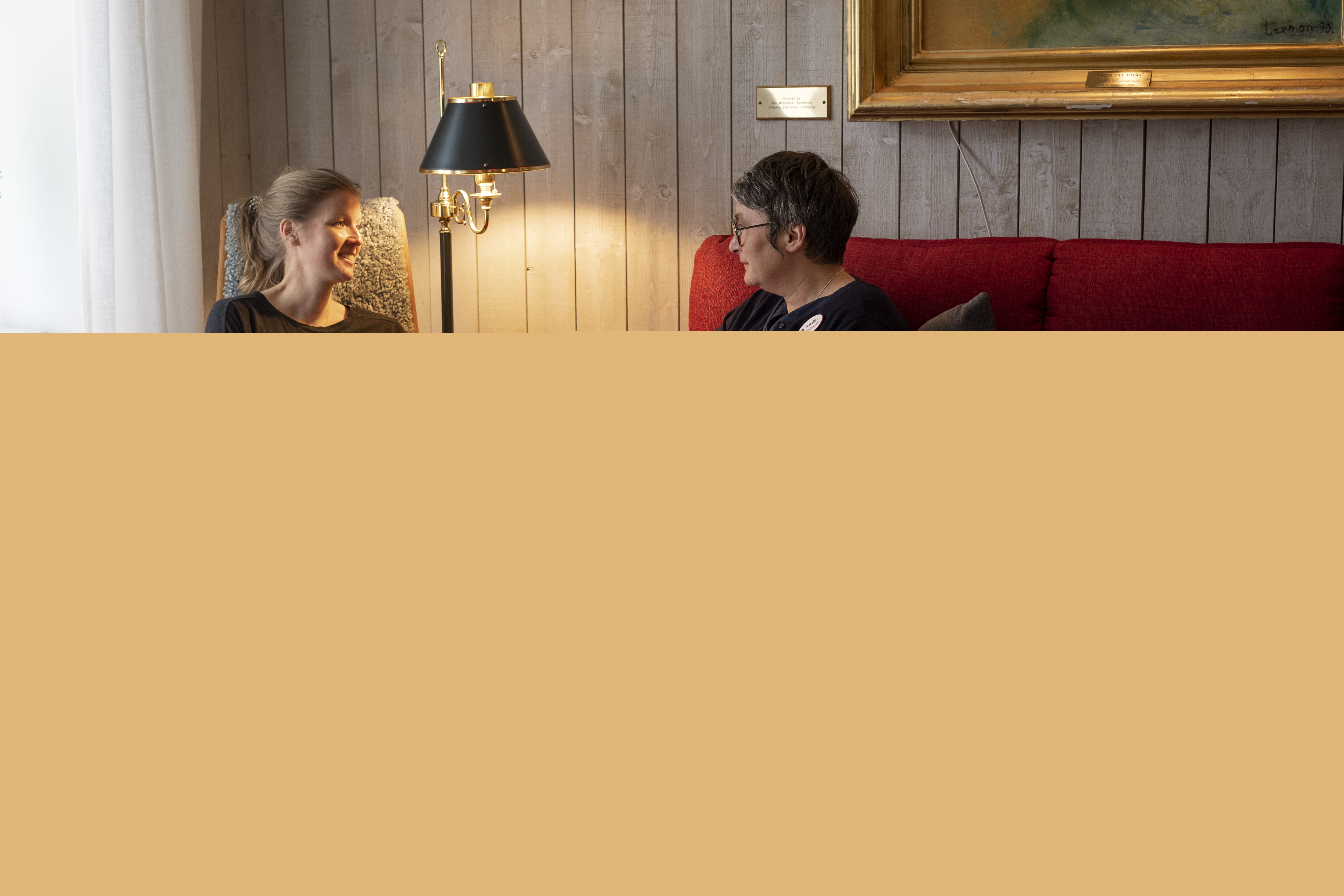 Två kvinnor sitter och samtalar i ett vardagsrum.