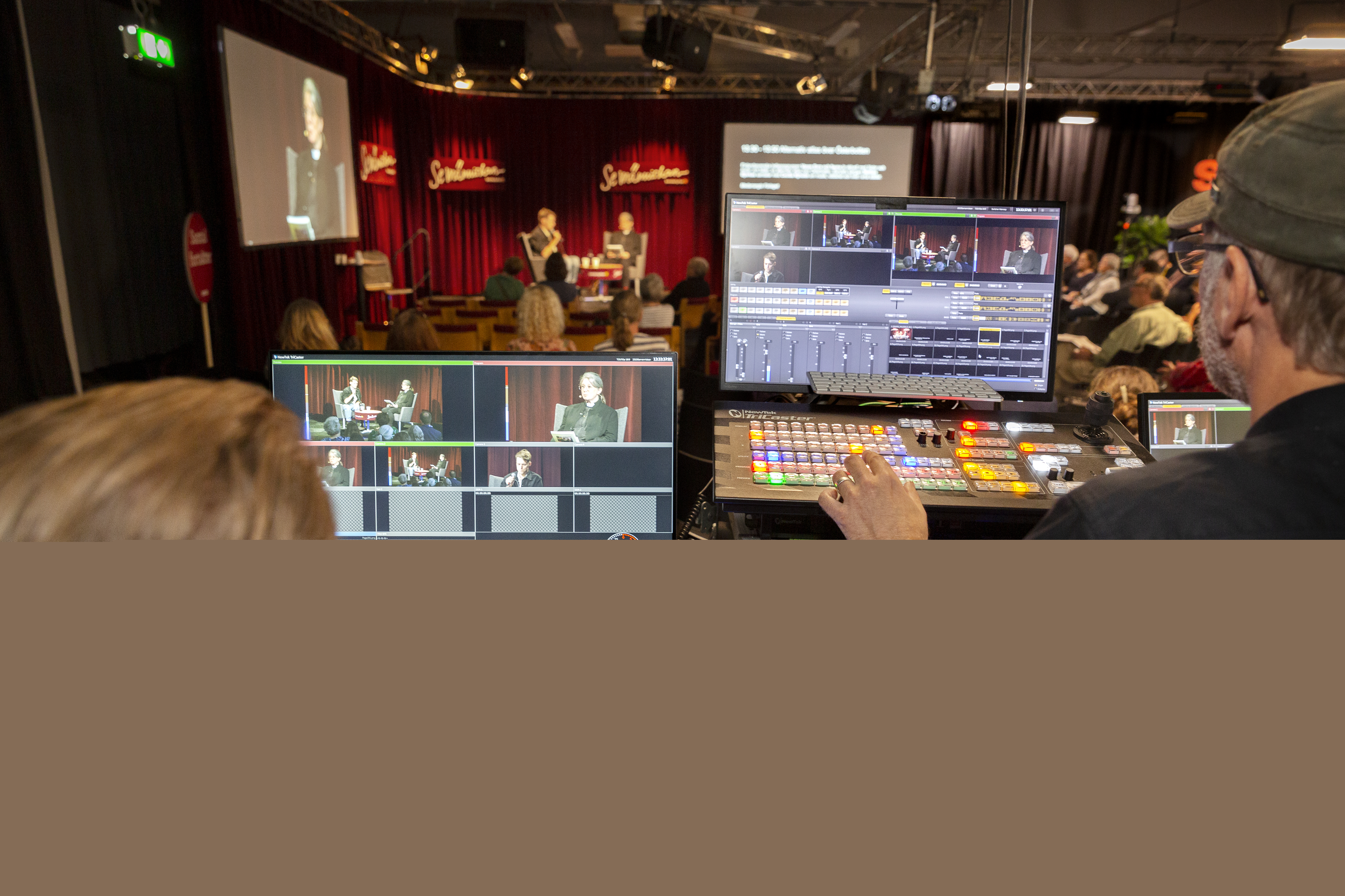 Två studiotekniker övervakar inspelningen av ett samtal på en scen.