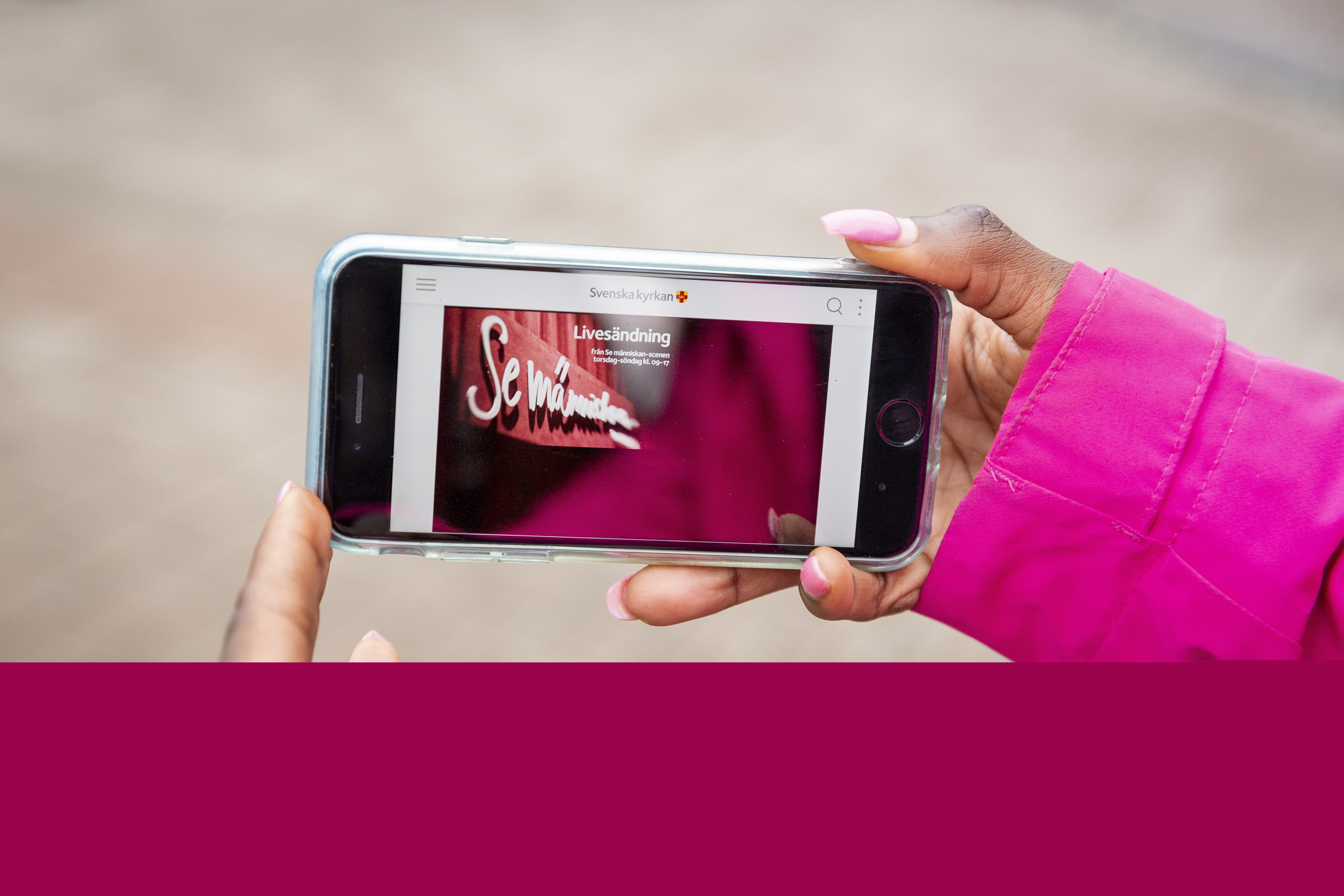 Ett par händer håller upp en mobil som visar en bild med texten Se människan.