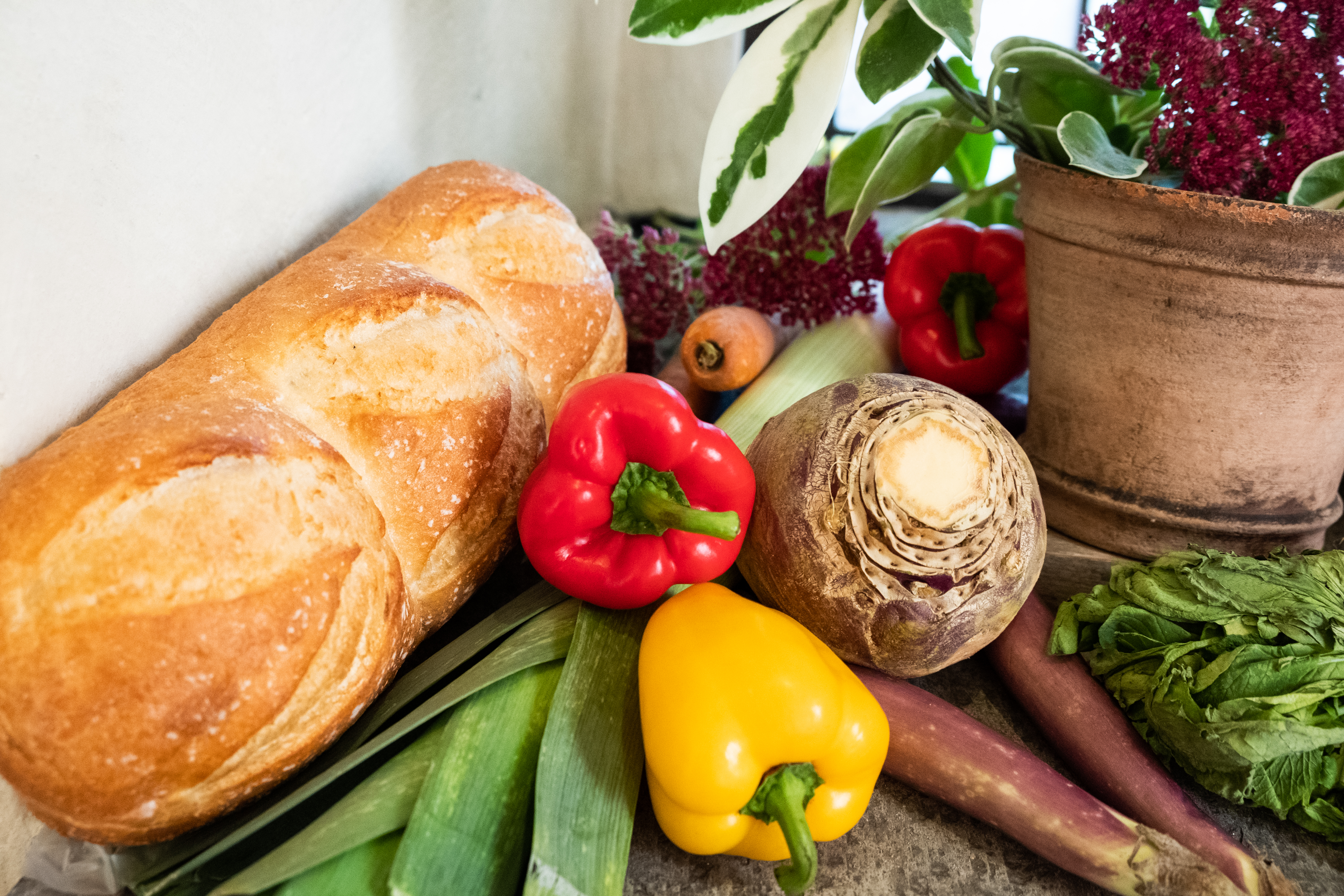 Ett bröd ligger i en hög med olika grönsaker.