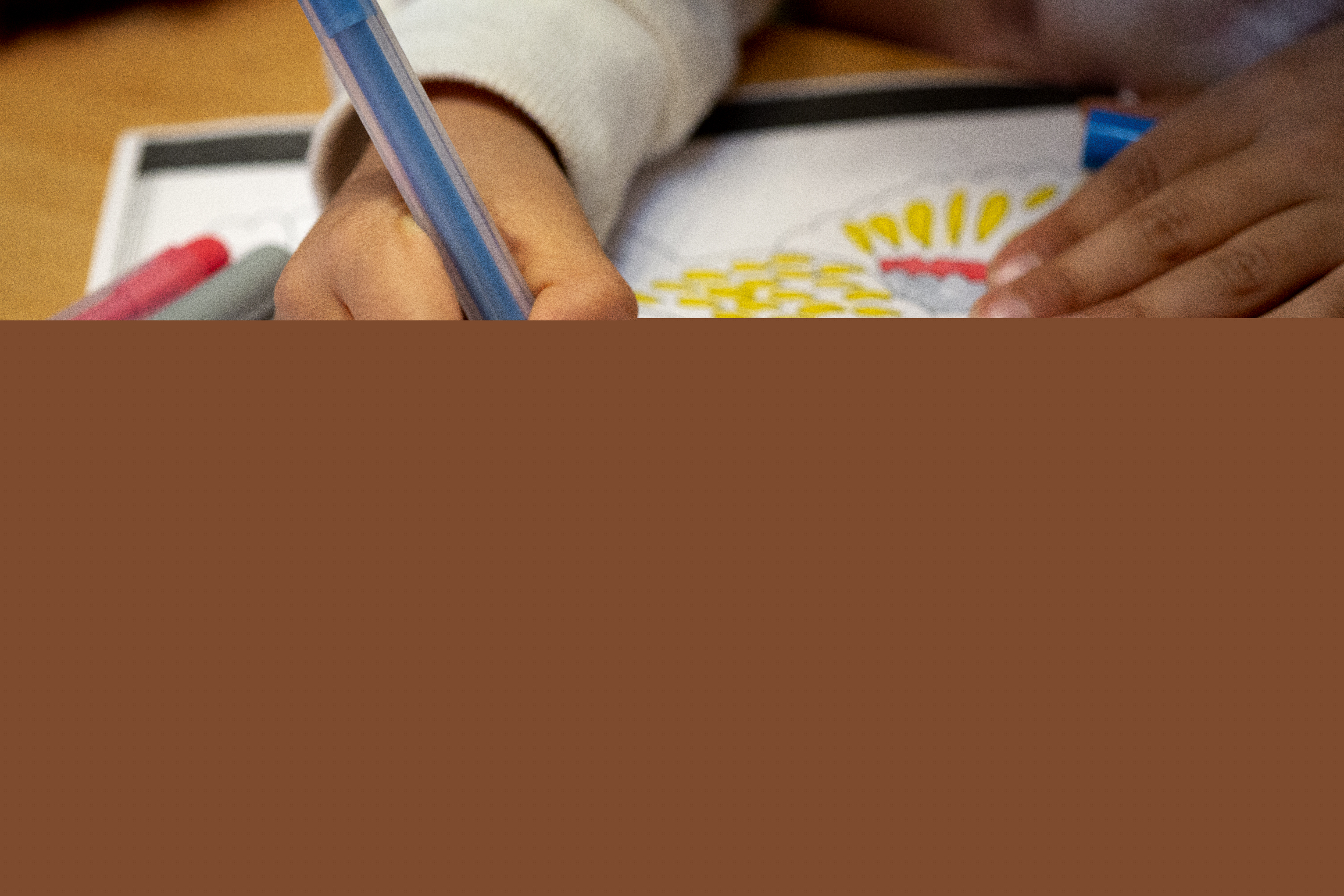 Någon färglägger en svartvit fågel på ett ritpapper.