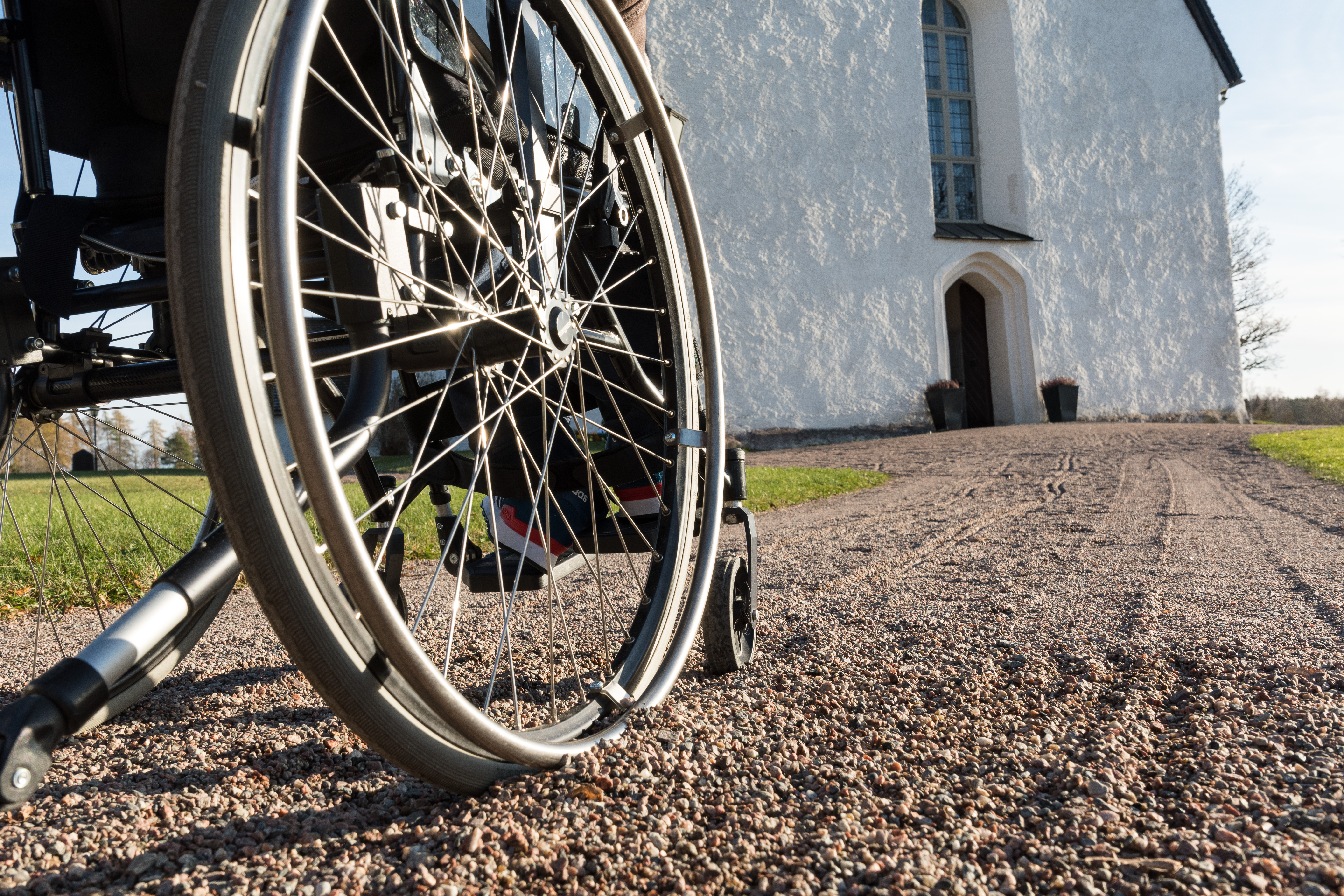 En rullstol kör längs grusgången mot kyrkan.