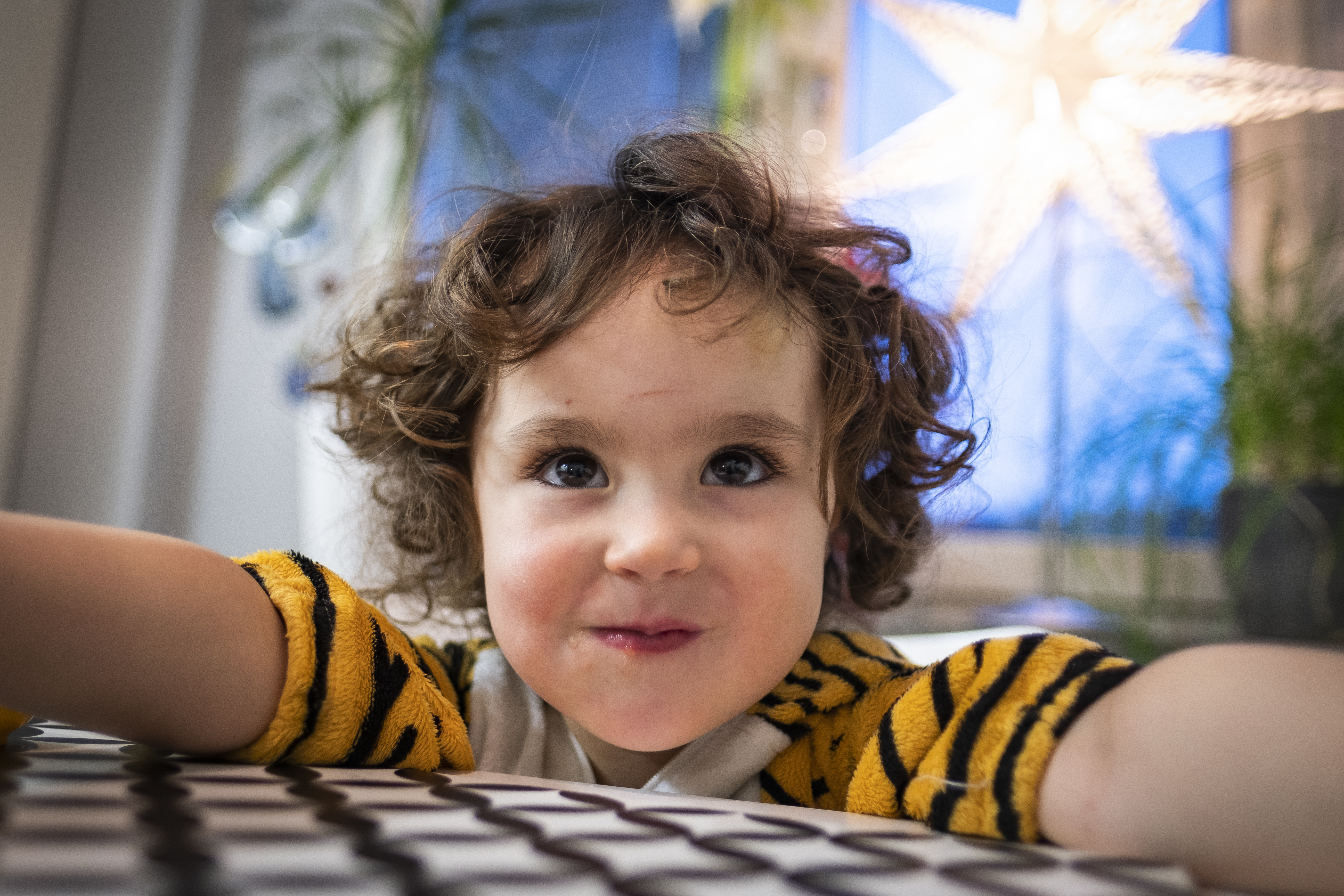 Ett litet barn med krulligt hår tittar nyfiket mot kameran.