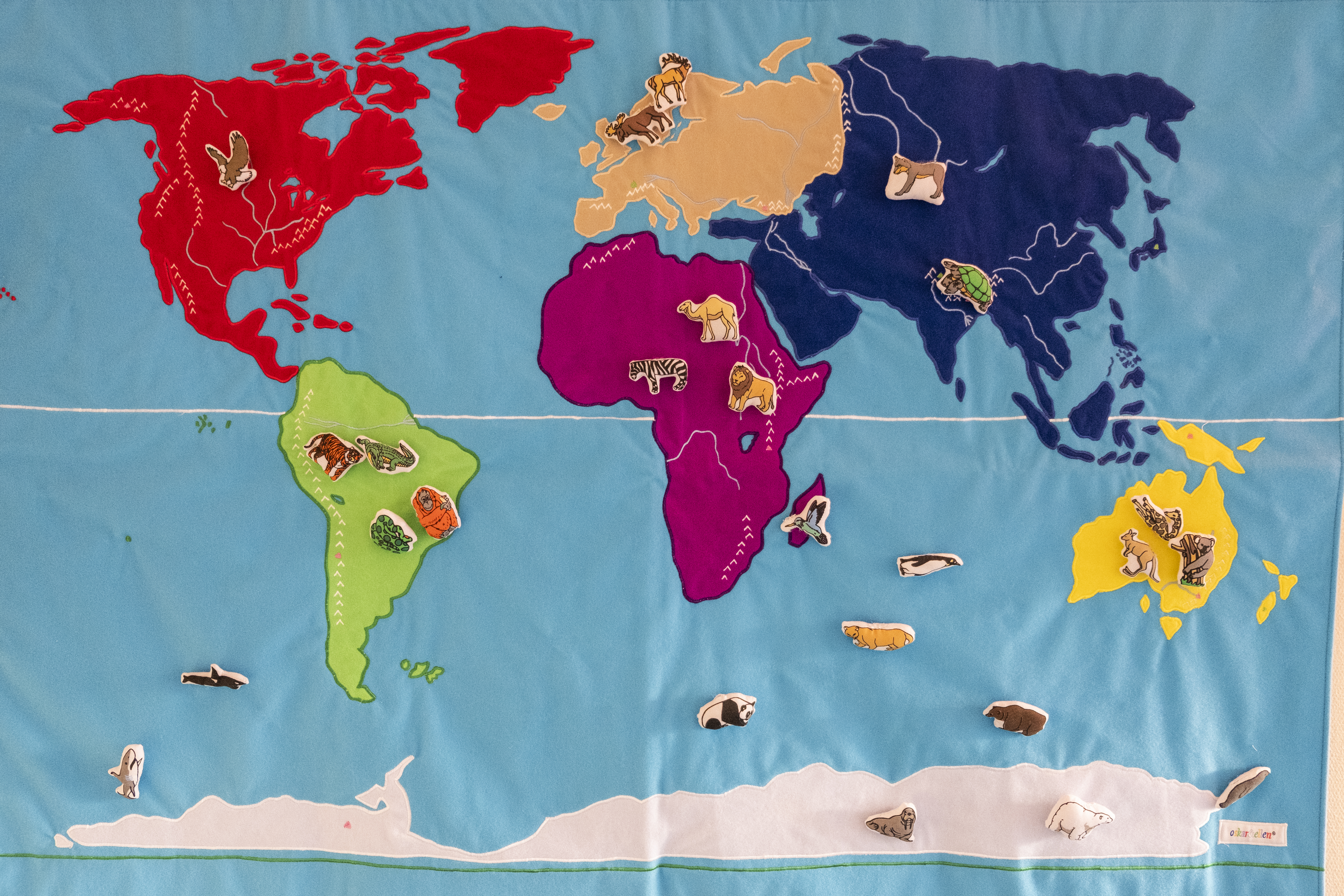 En färggrann världskarta med små djur placerade i de olika världsdelar de finns.