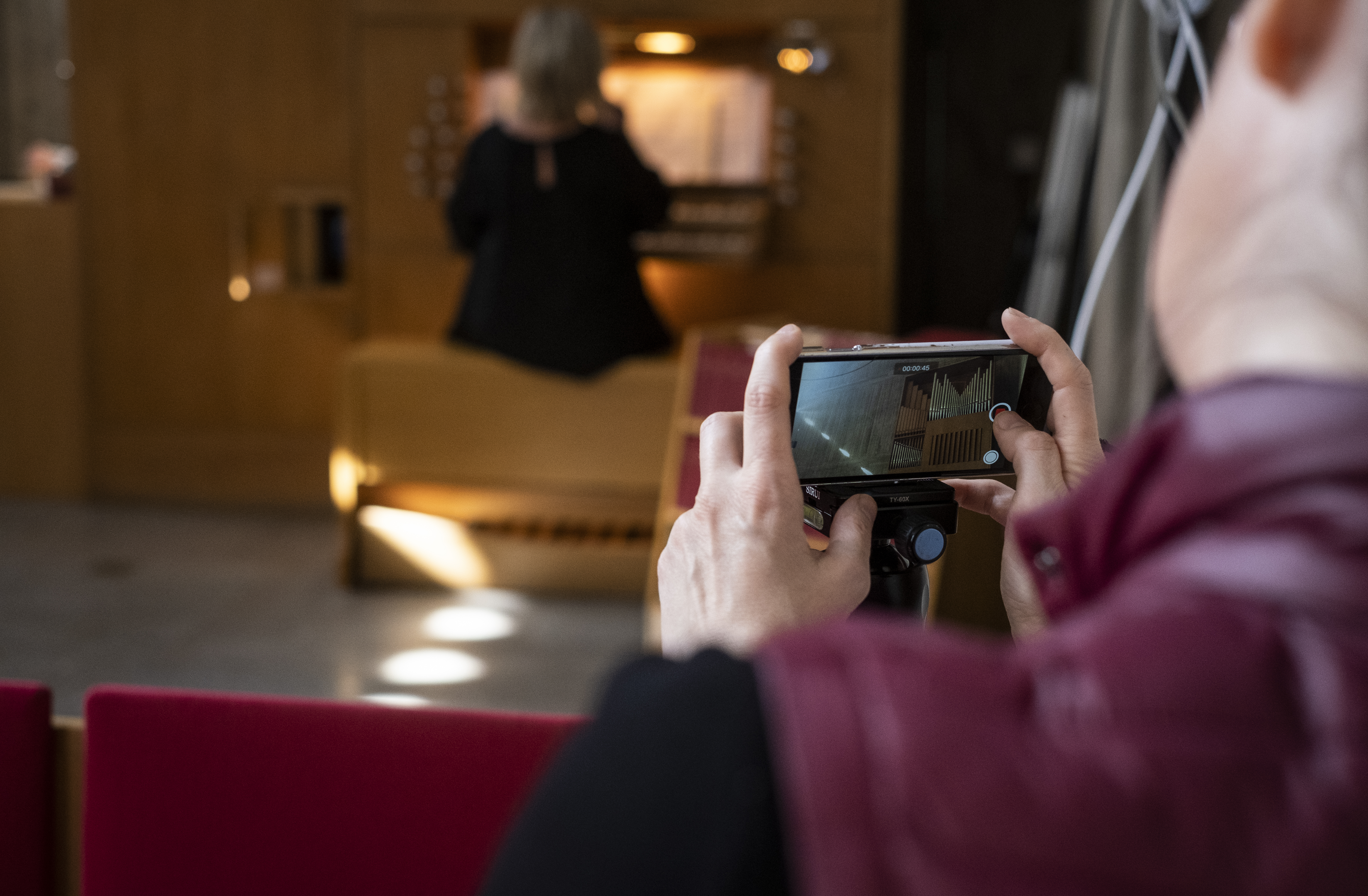 Någon filmar med mobiltelefonen en kvinna som spelar orgel.