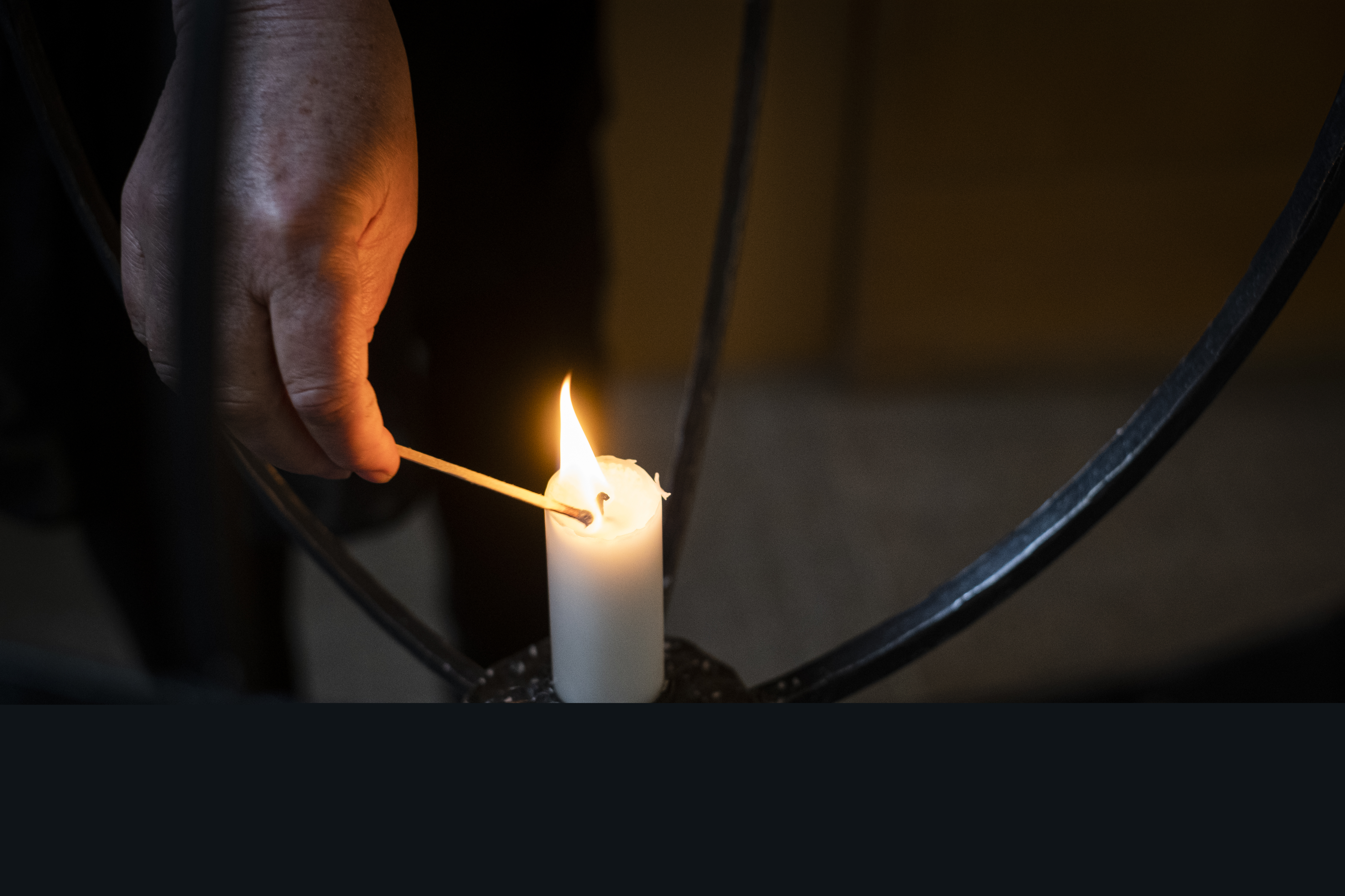 Joku sytyttää kynttelikön kynttilän.