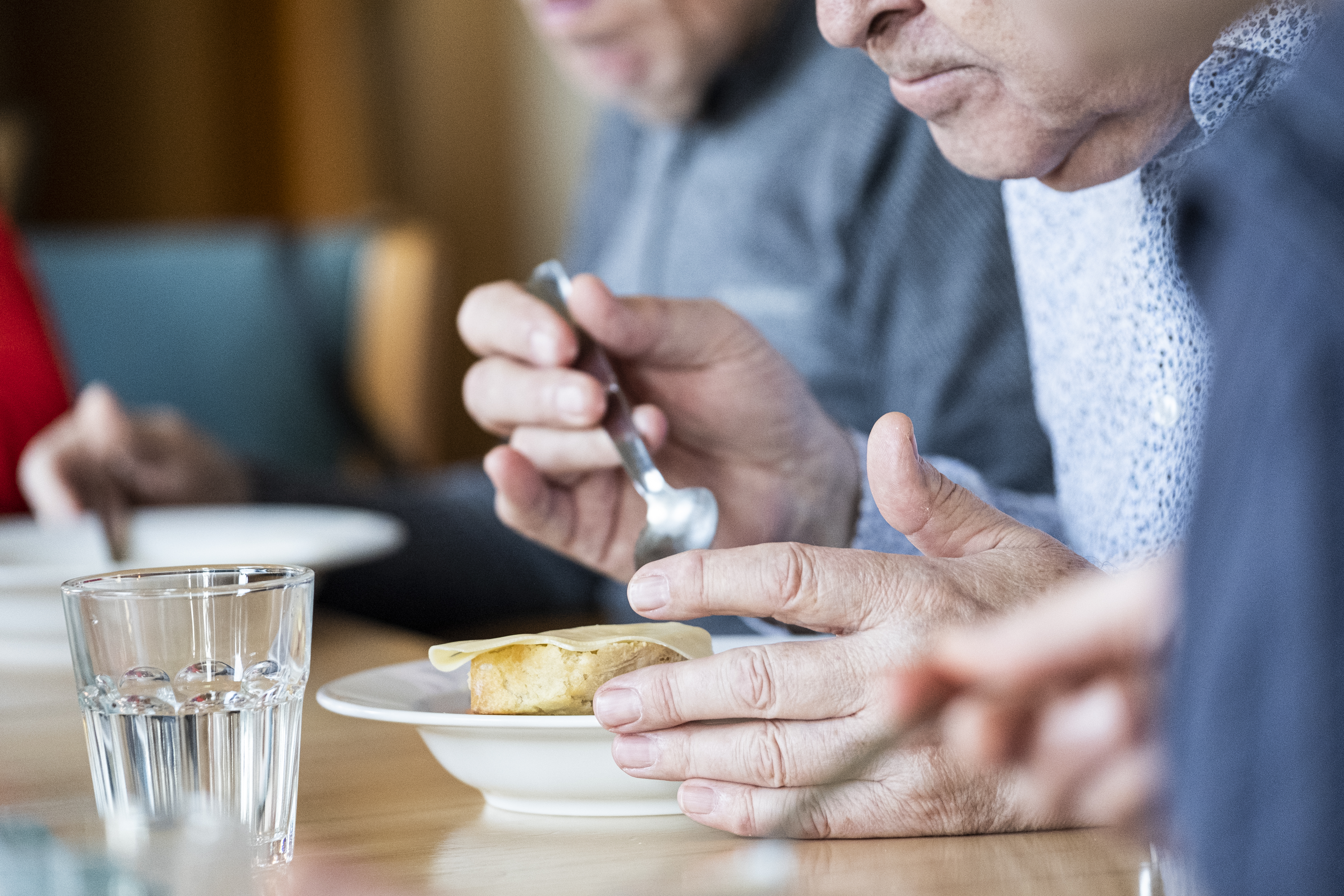 Några personer sitter runt matbordet och äter.