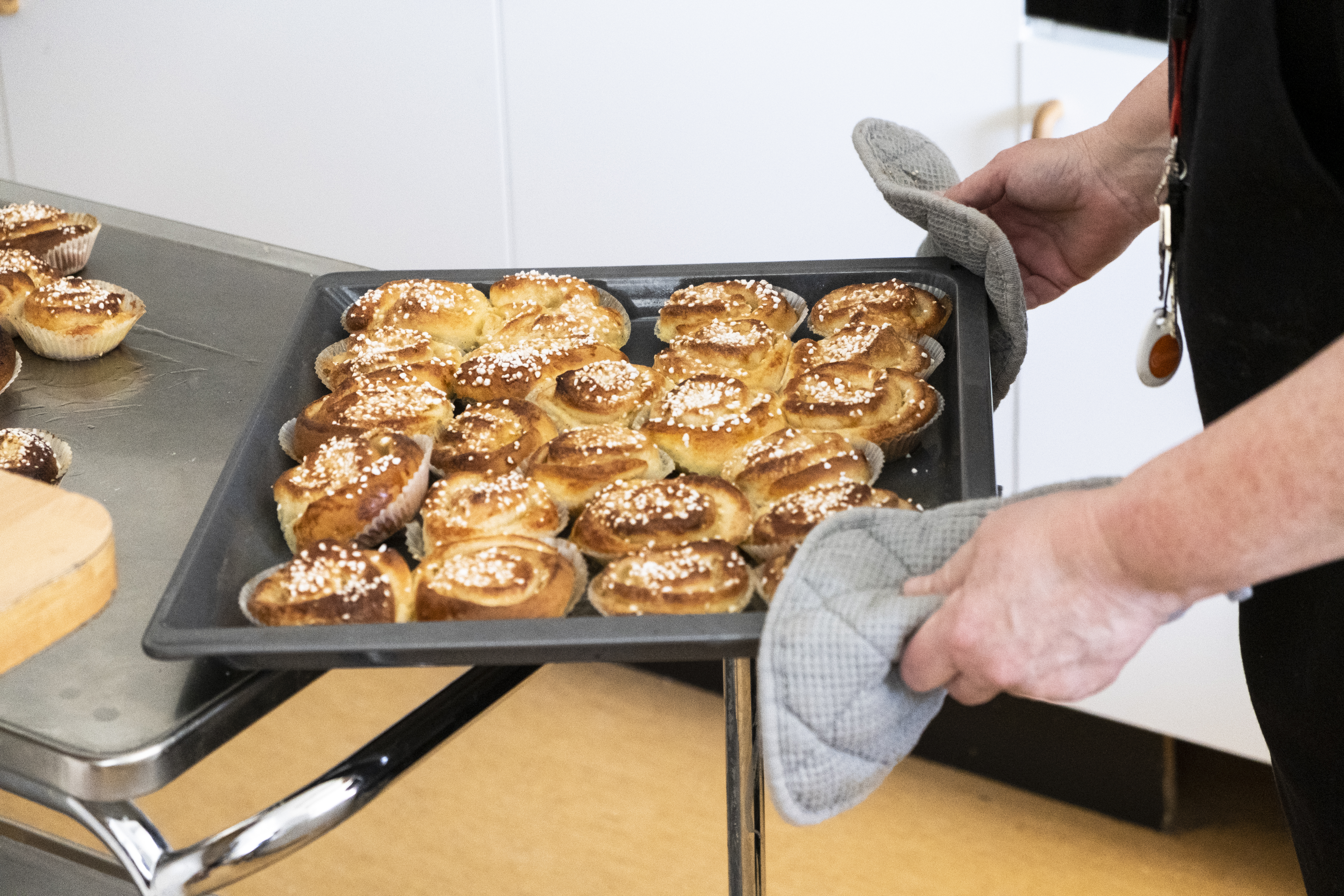 Någon ställer ifrån sig en plåt nybakta kanelbullar.