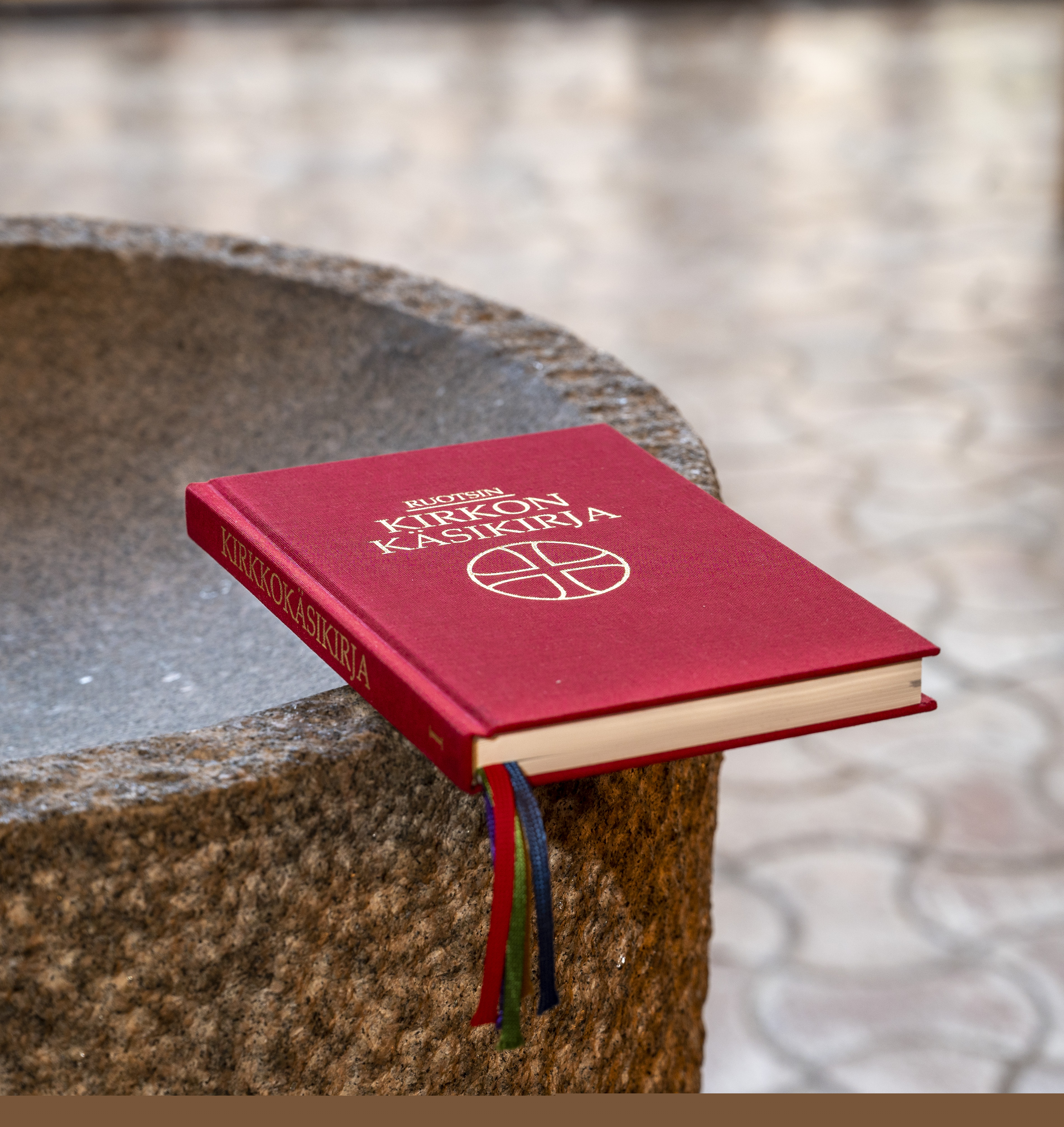 En finsk kyrkohandbok ligger på dopfuntens kant.