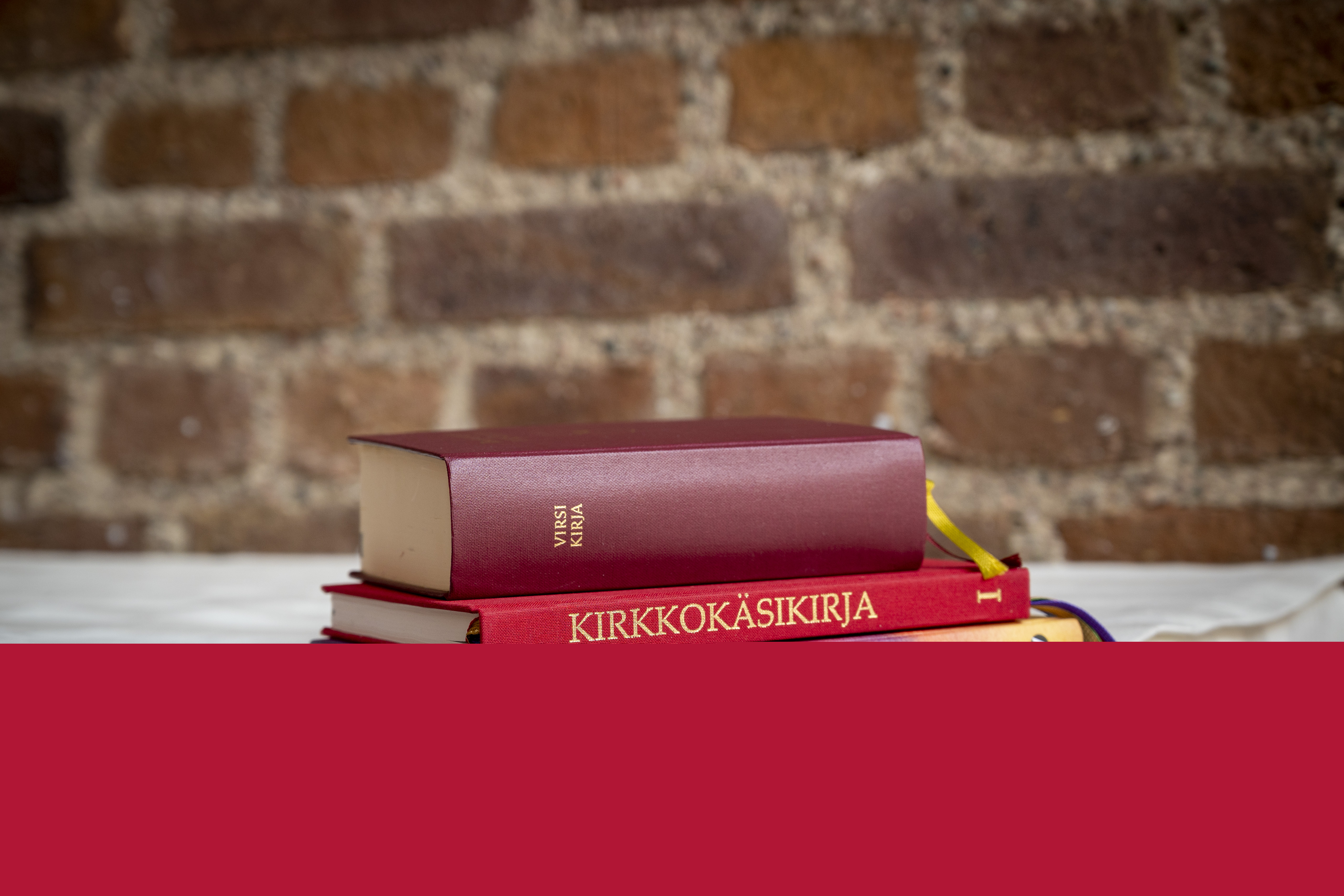 En finsk kyrkohandbok och två psalmböcker ligger på kanten av ett altare.