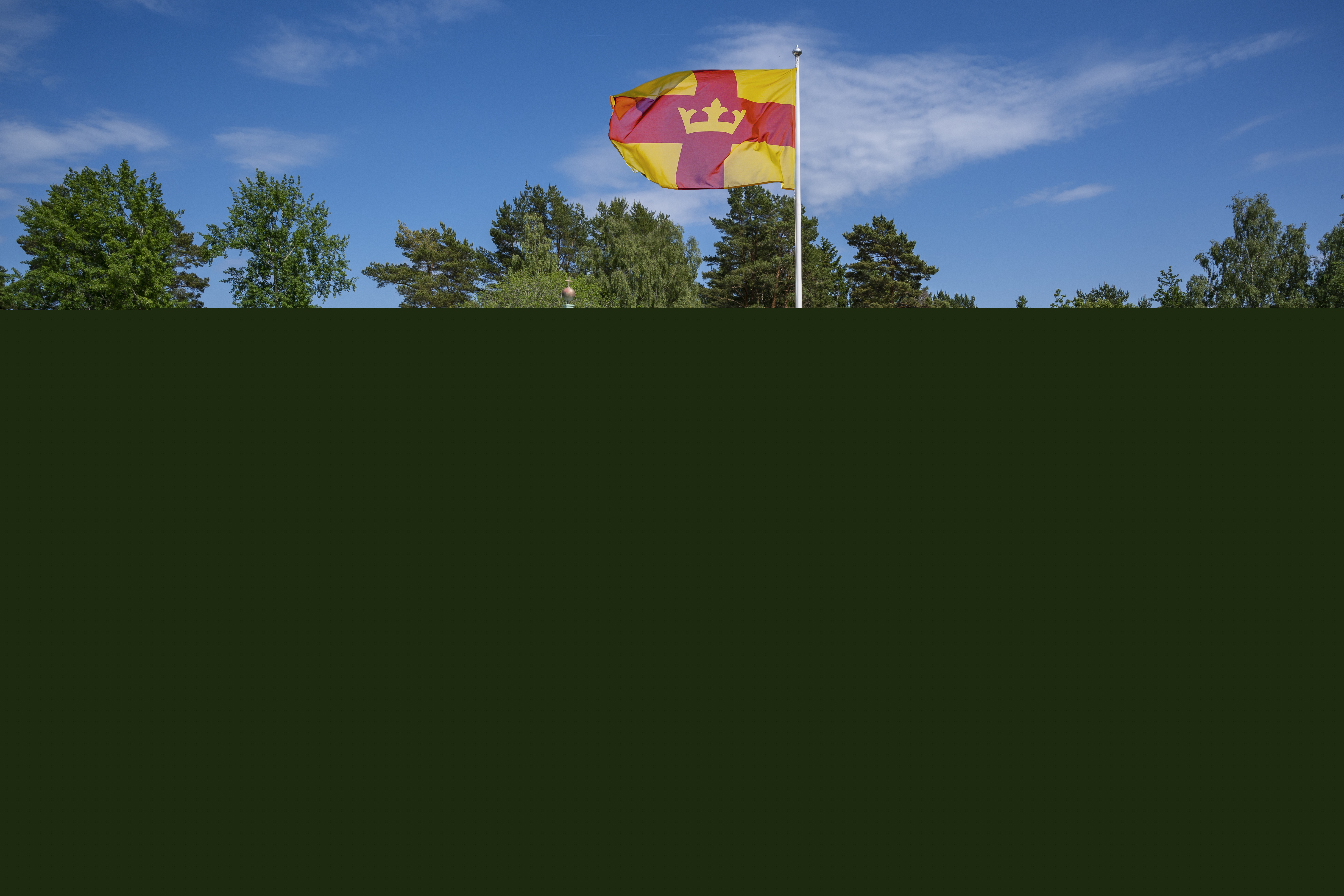 Magdalenakyrkan i Bålsta en solig dag. Svenska kyrkans flagga vajar utanför.