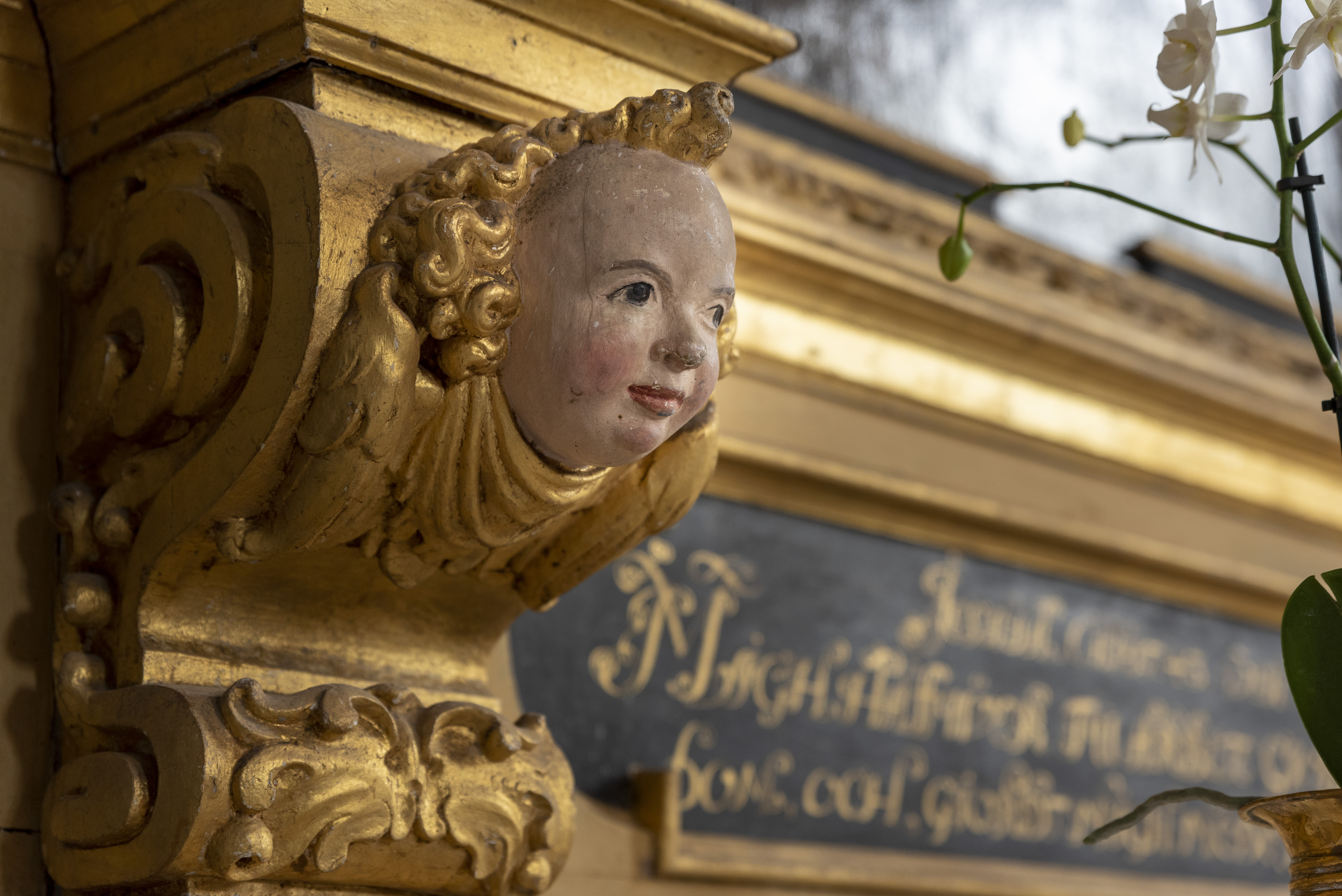 En ängels ansikte i ett guldmålat träornament.